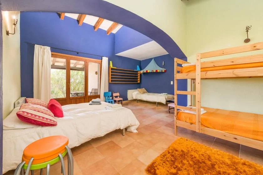 Un dormitorio colorido con camas, una litera y un gran arco en el techo.