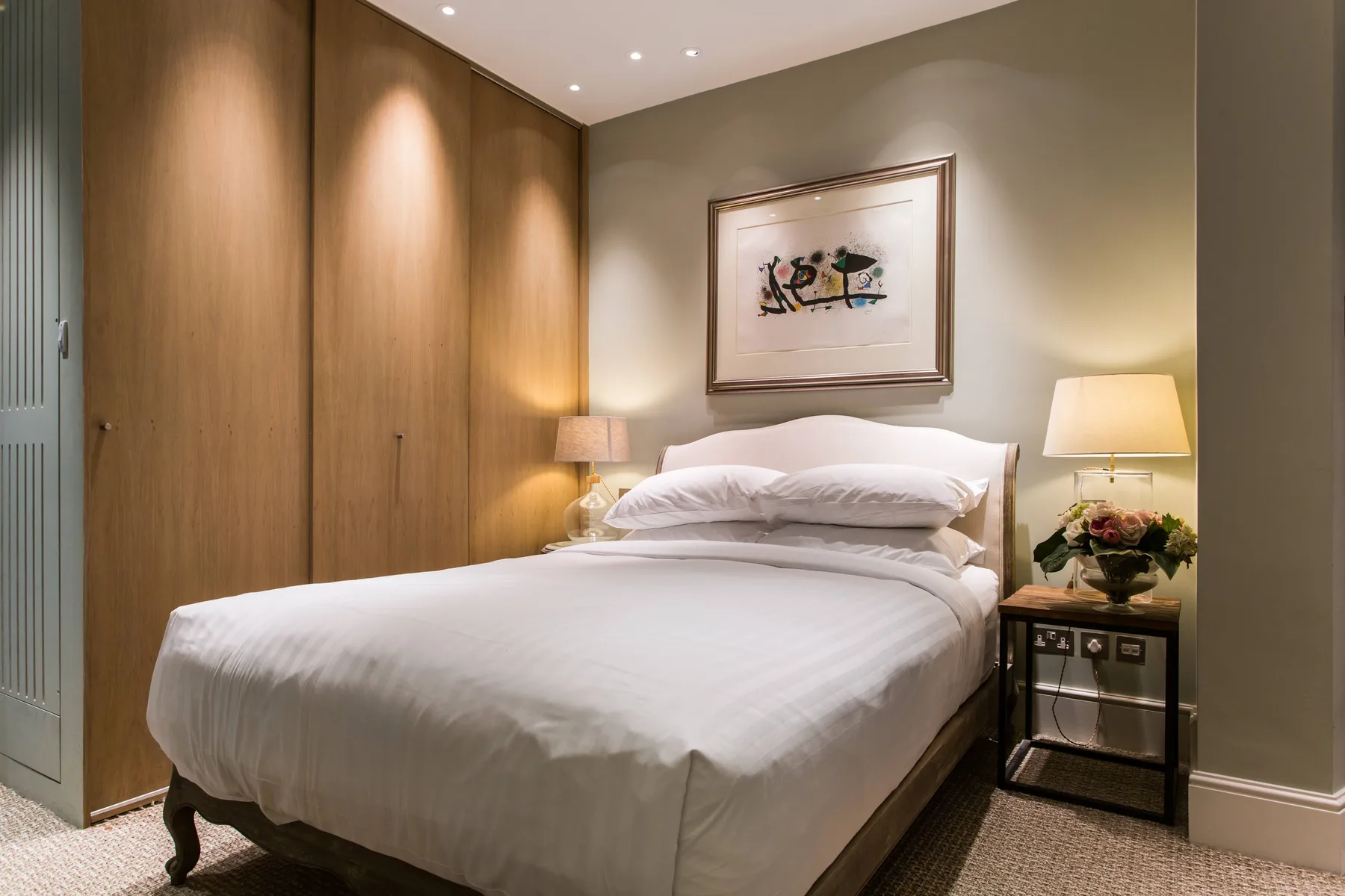 A bedroom with a neatly made bed and framed artwork above the headboard.