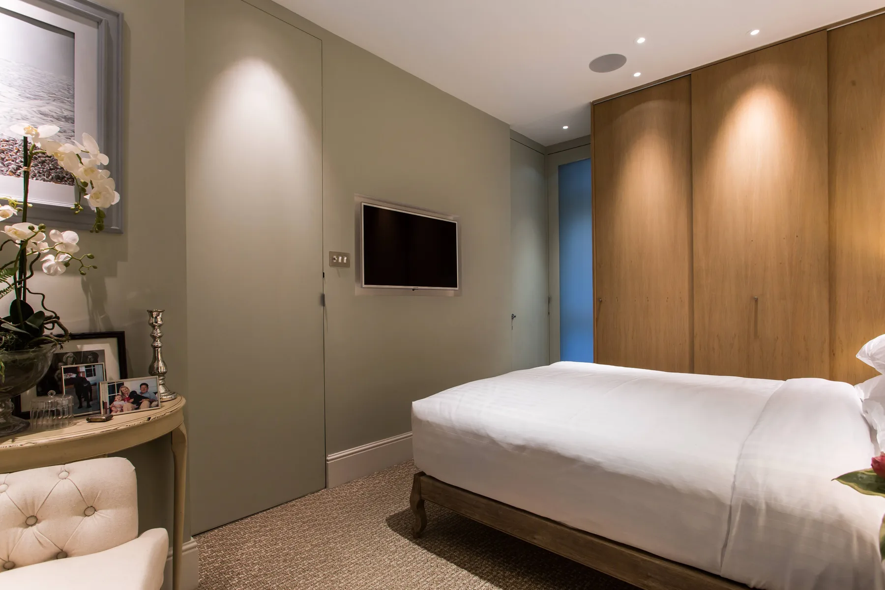A bedroom with a neatly made bed and a television mounted on the wall.