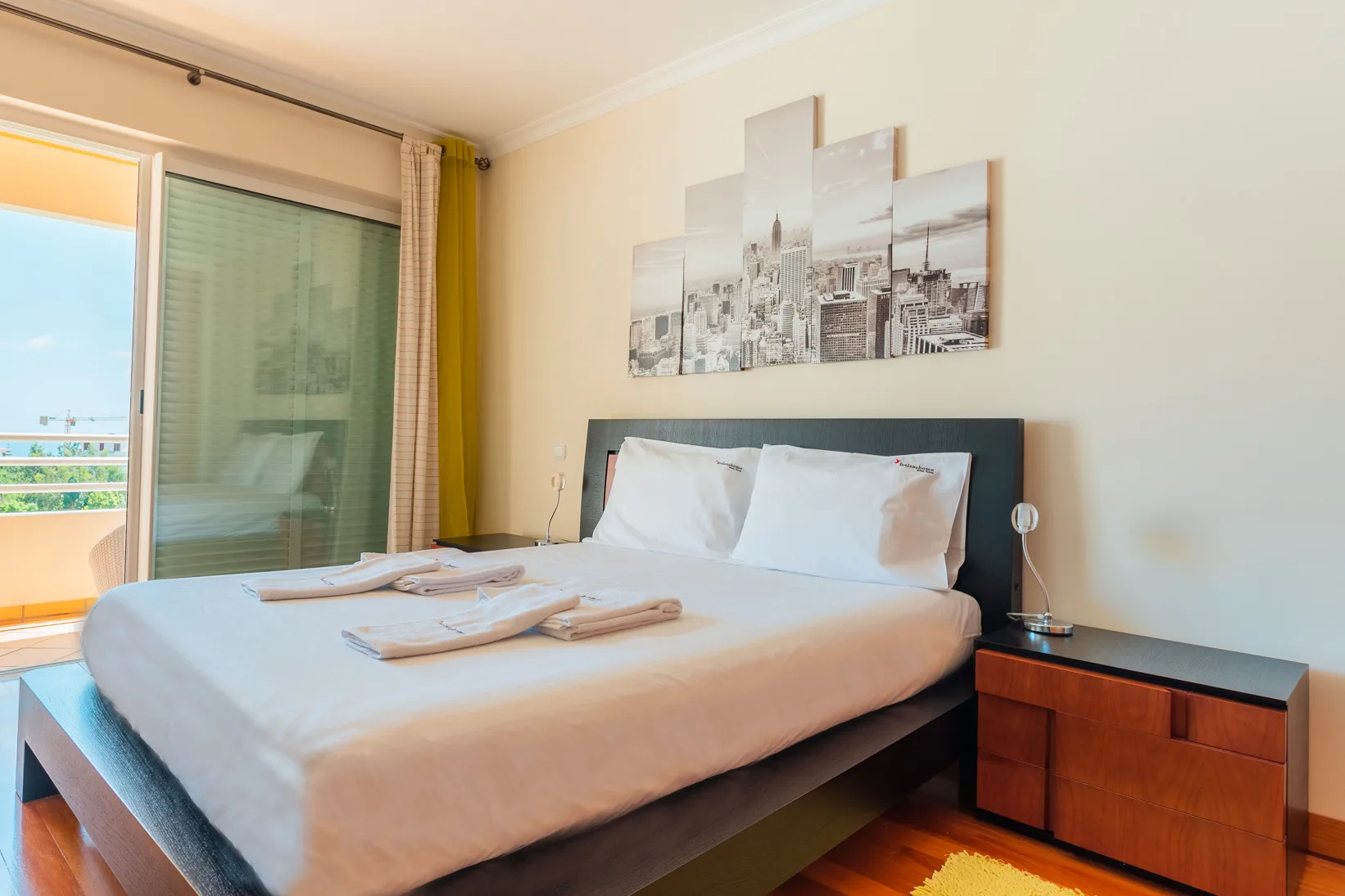 Un dormitorio con una cama tendida junto a una puerta de vidrio que da a un balcón.