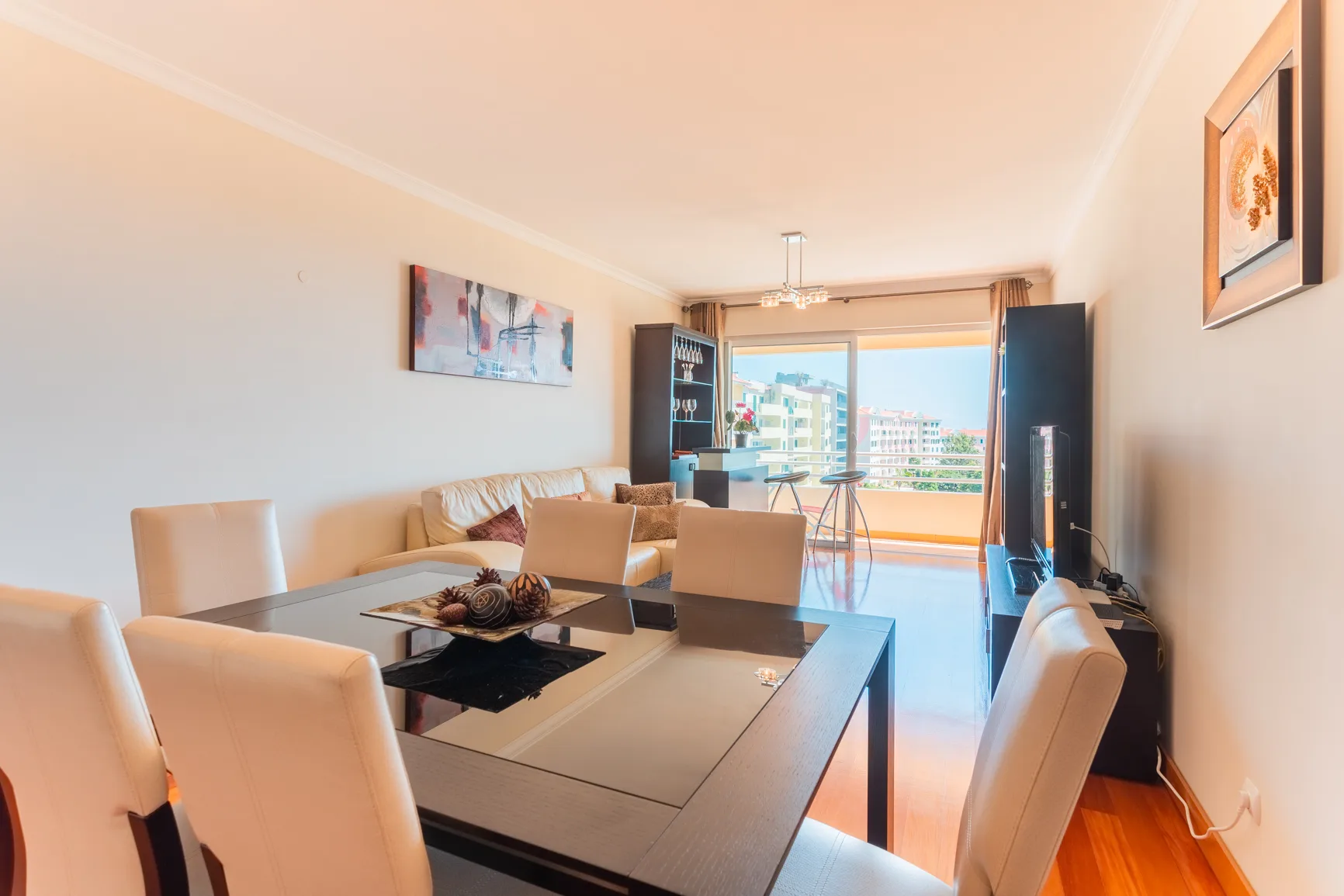 A dining and living area opens onto a balcony through large glass doors.