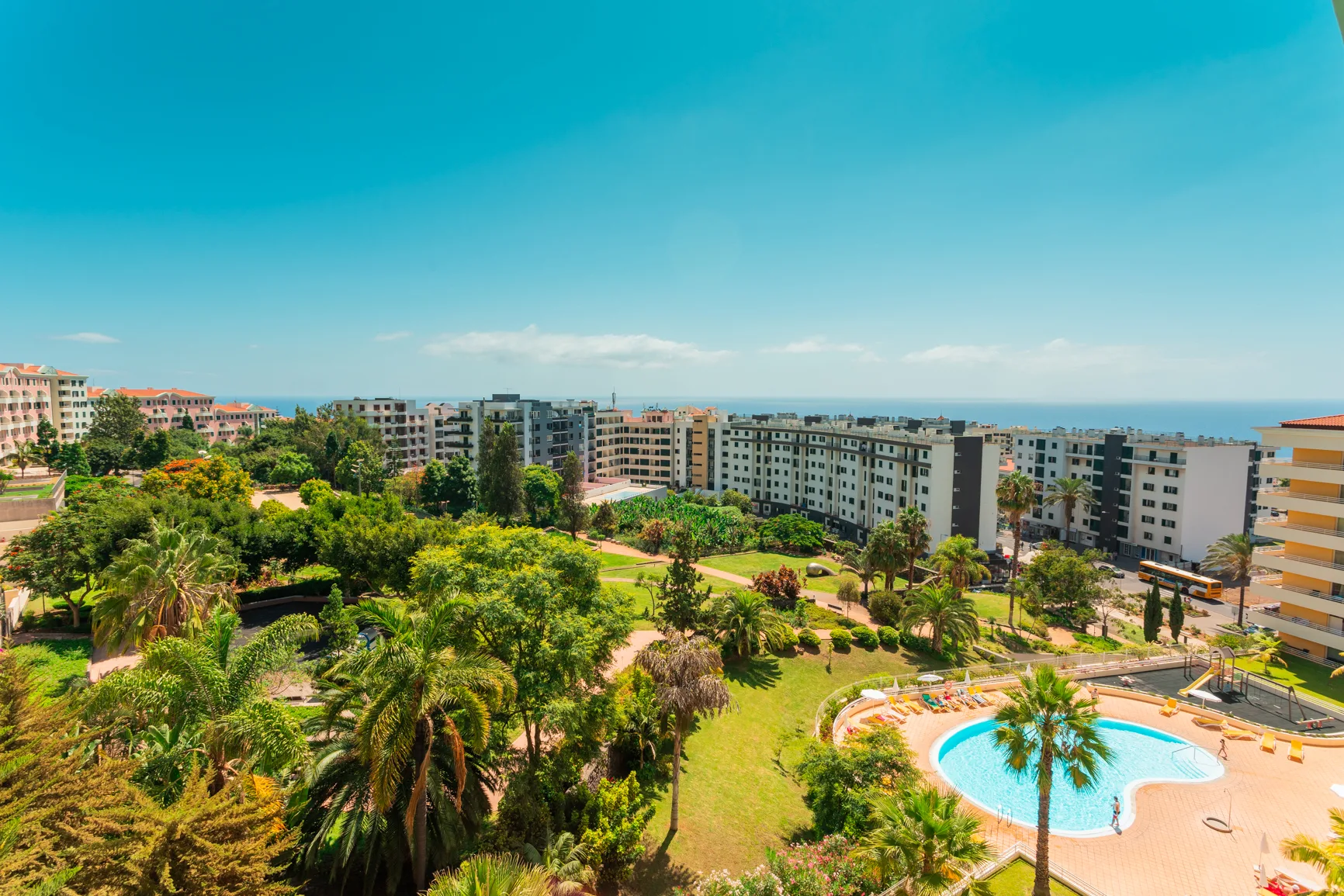 A landscaped courtyard with a swimming pool and apartment buildings beyond.