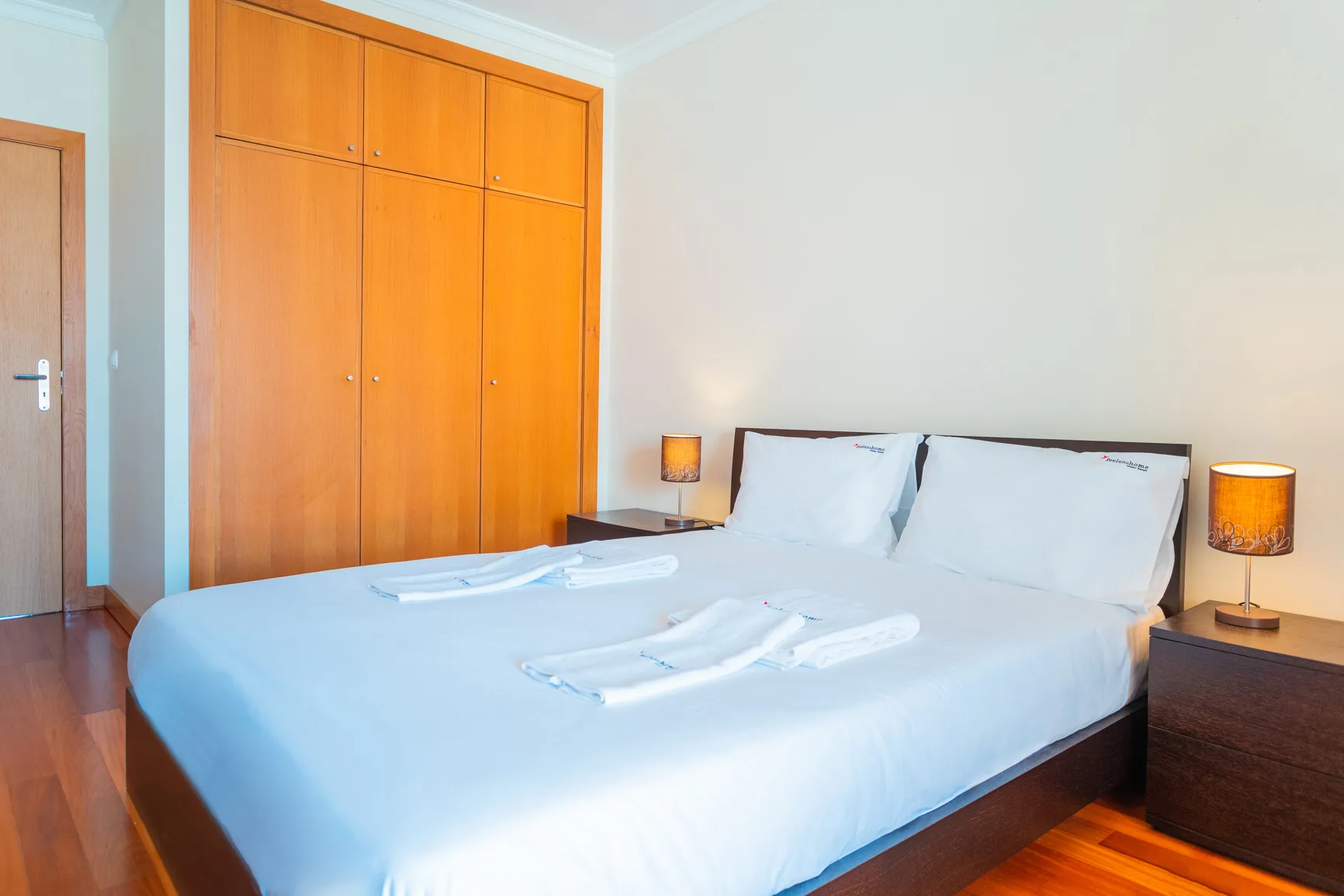A bedroom with a large bed and wooden wardrobe.