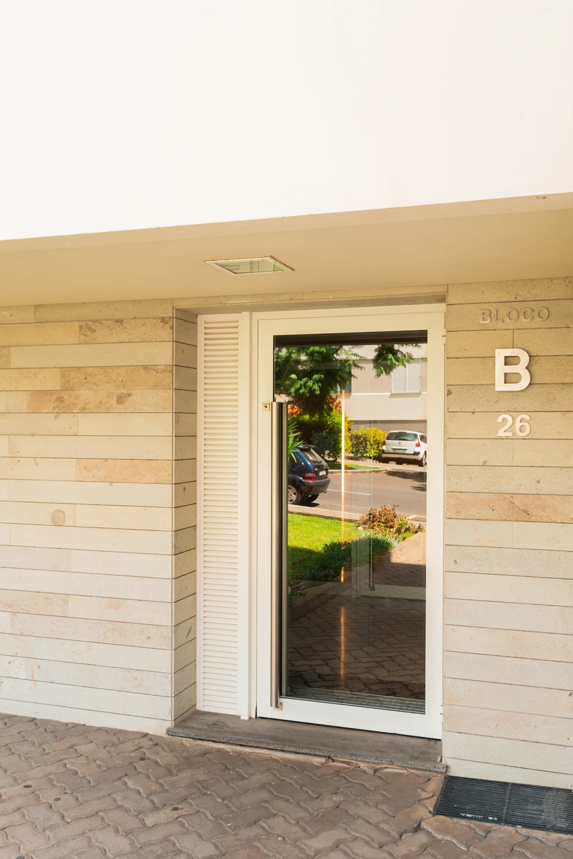 An apartment building entrance with a glass door and block lettering.
