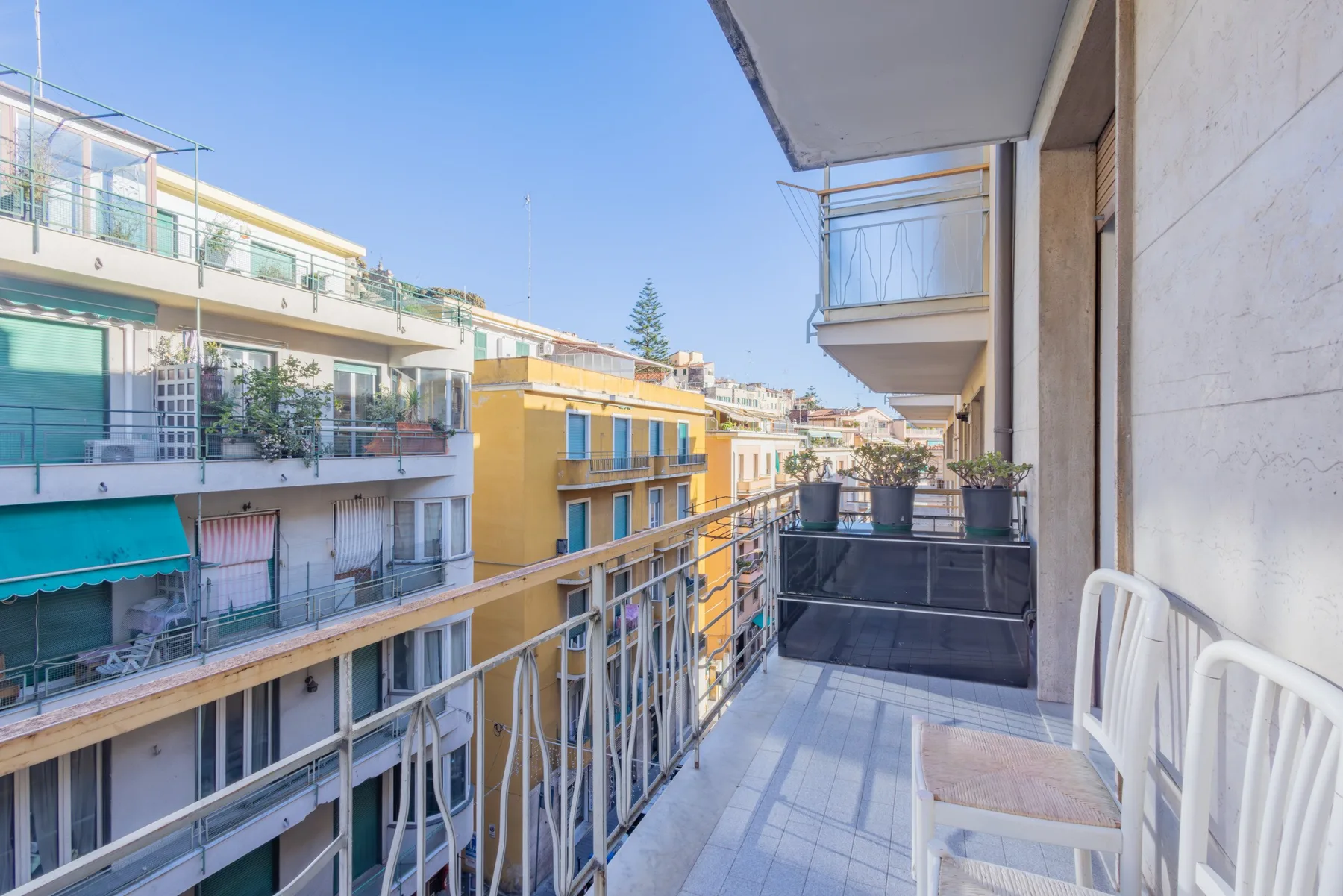 A balcony overlooks neighboring buildings, with metal railings and seating.