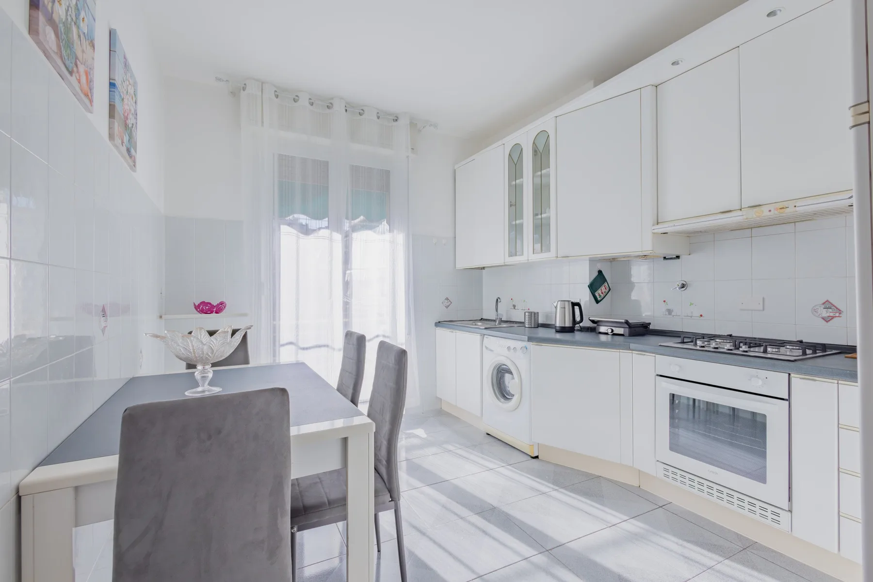 A bright kitchen with a dining table and white cabinetry.