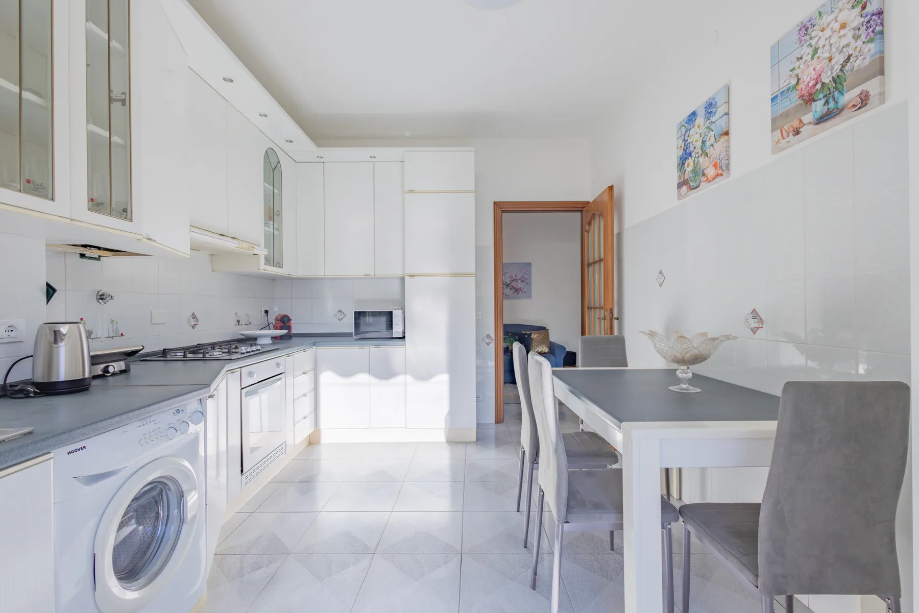A bright kitchen and dining area with white cabinets and a table.