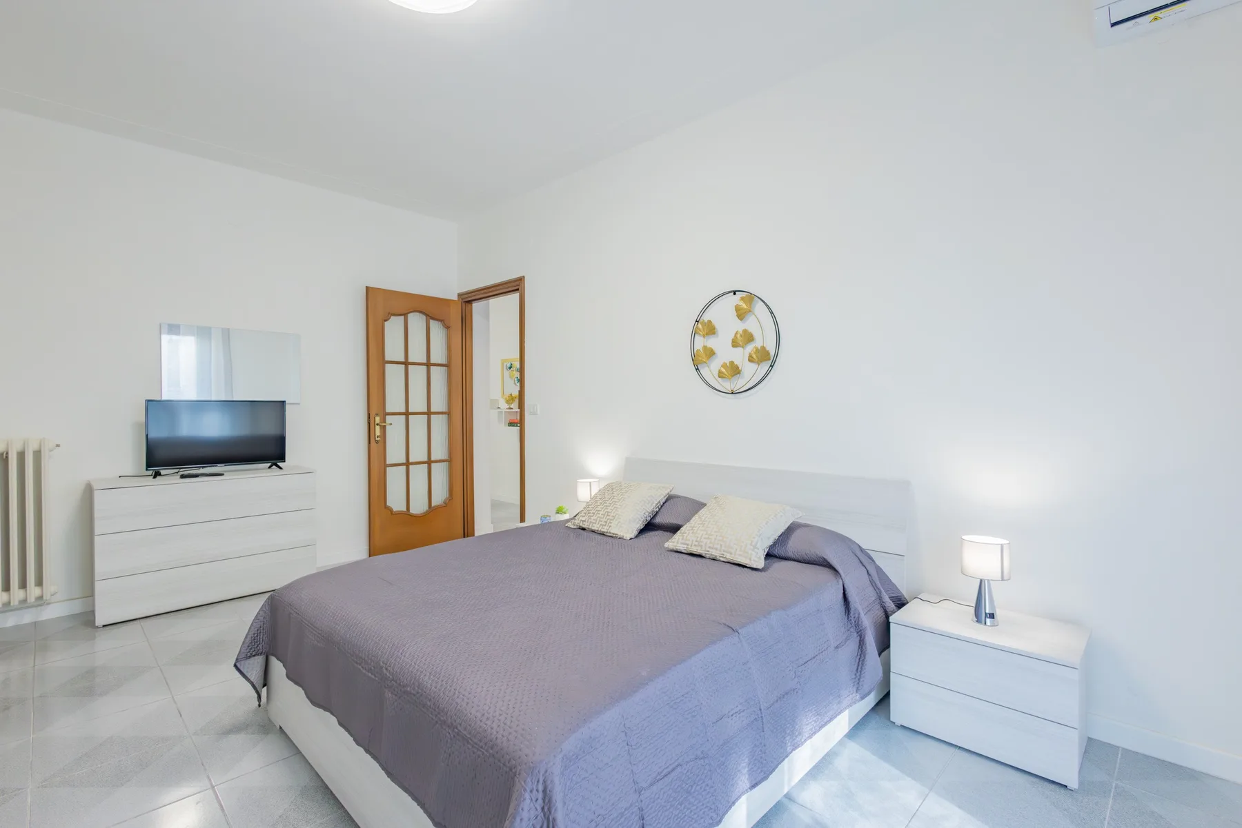 A bedroom with a double bed, bedside table, and television.