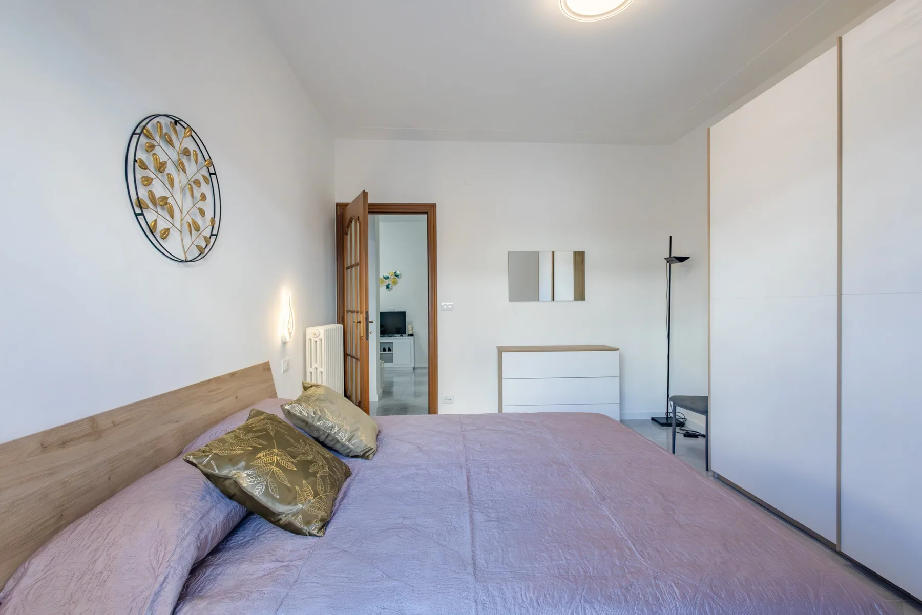 A bedroom with a bed, decorative wall art, and a floor lamp.