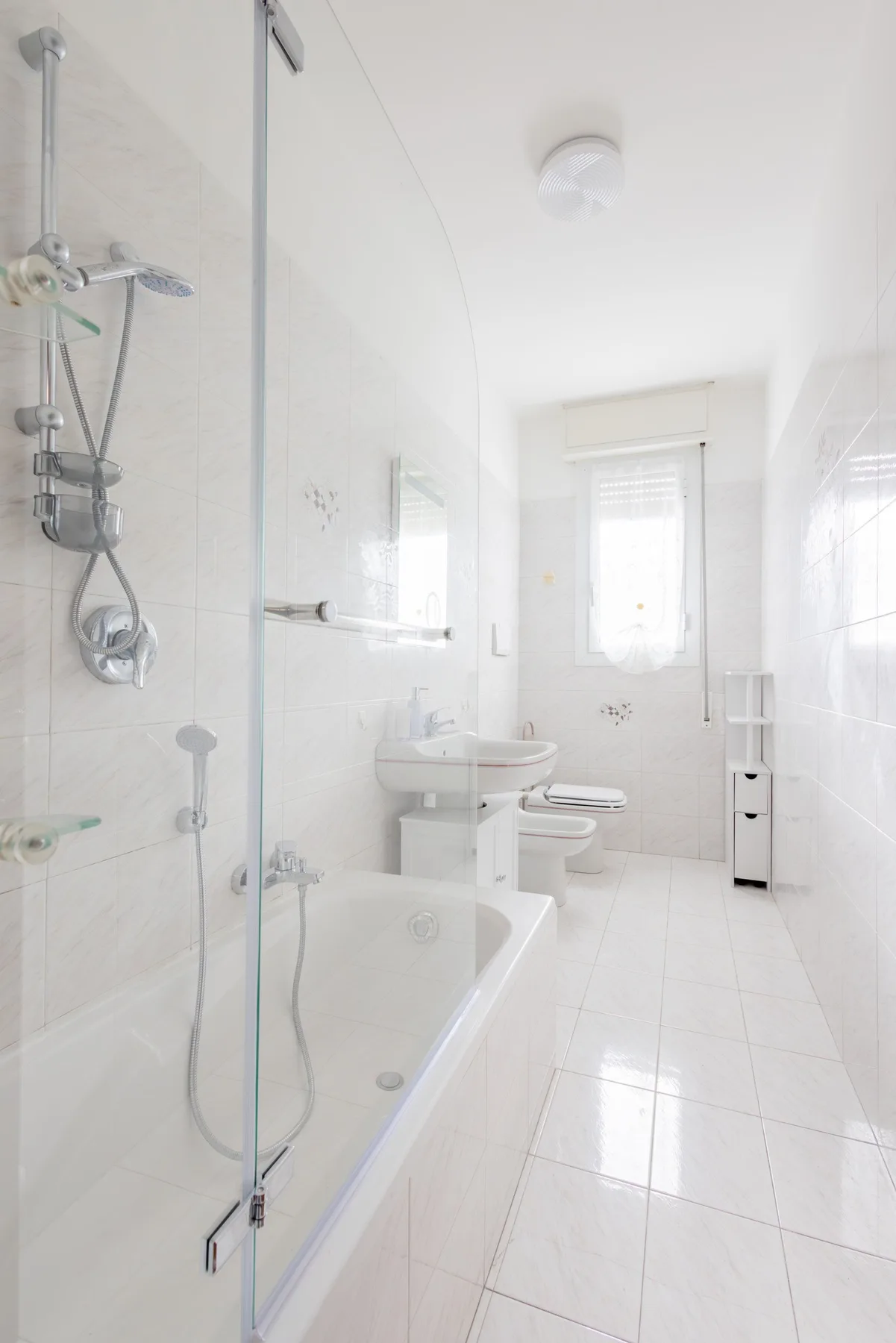 A bright bathroom with a bathtub, shower, and sink.