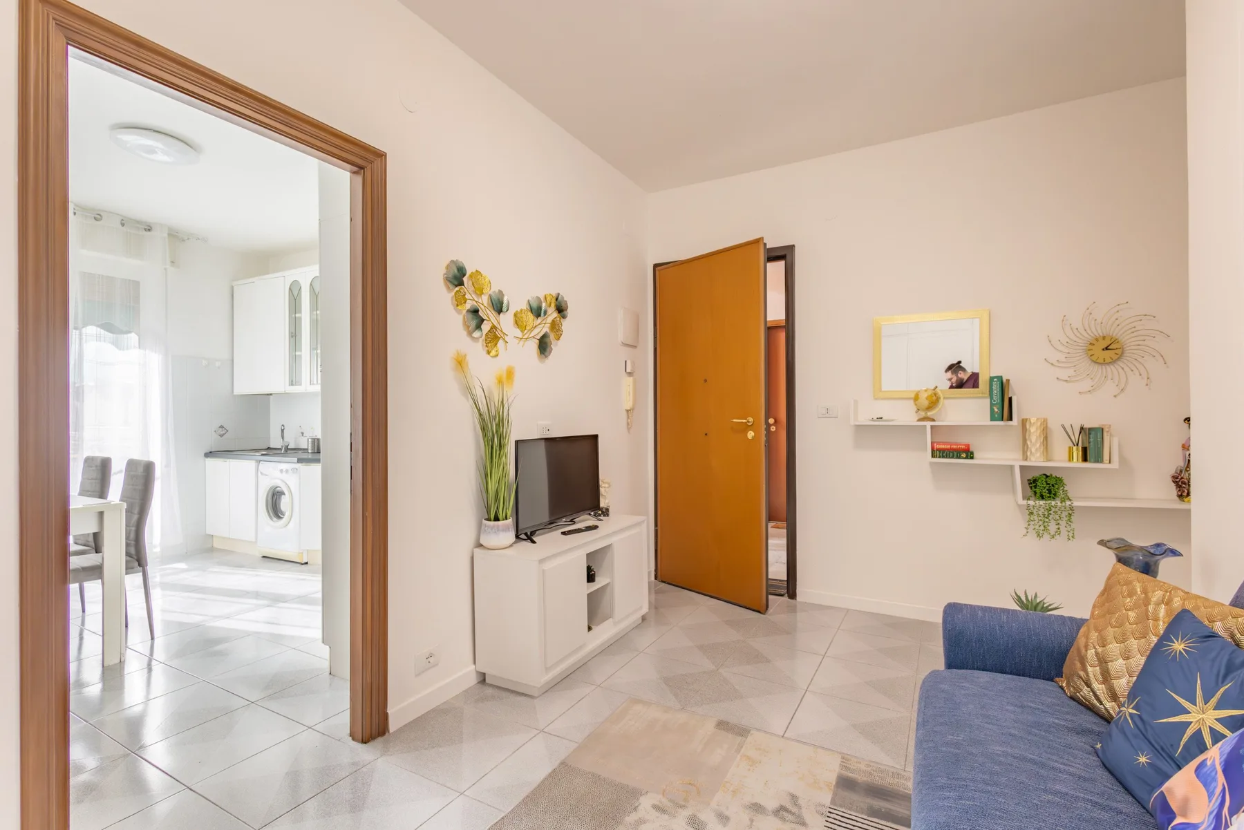 A bright living room with a blue seating area and an open doorway to the kitchen.