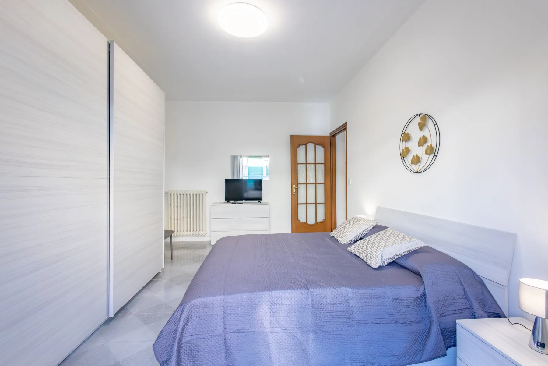 A bedroom with a bed, a wardrobe, and a television on a dresser.