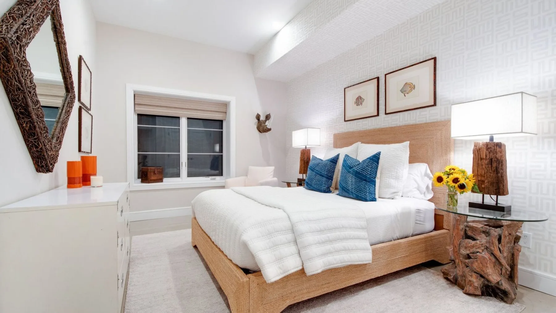 Un dormitorio luminoso con una cama bien tendida y cojines azules.