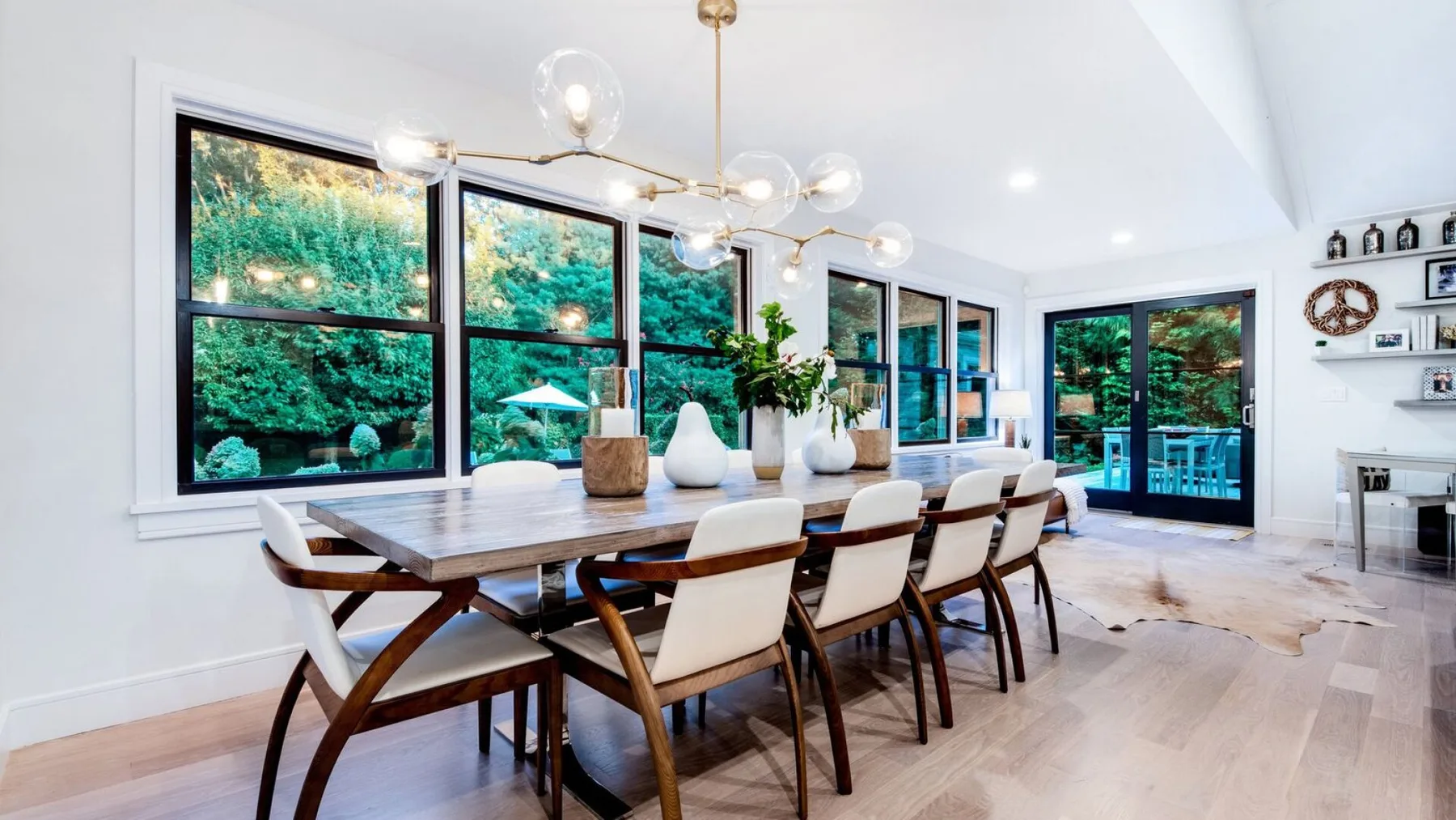Un comedor luminoso con una mesa larga y grandes ventanas con vistas a la vegetación.