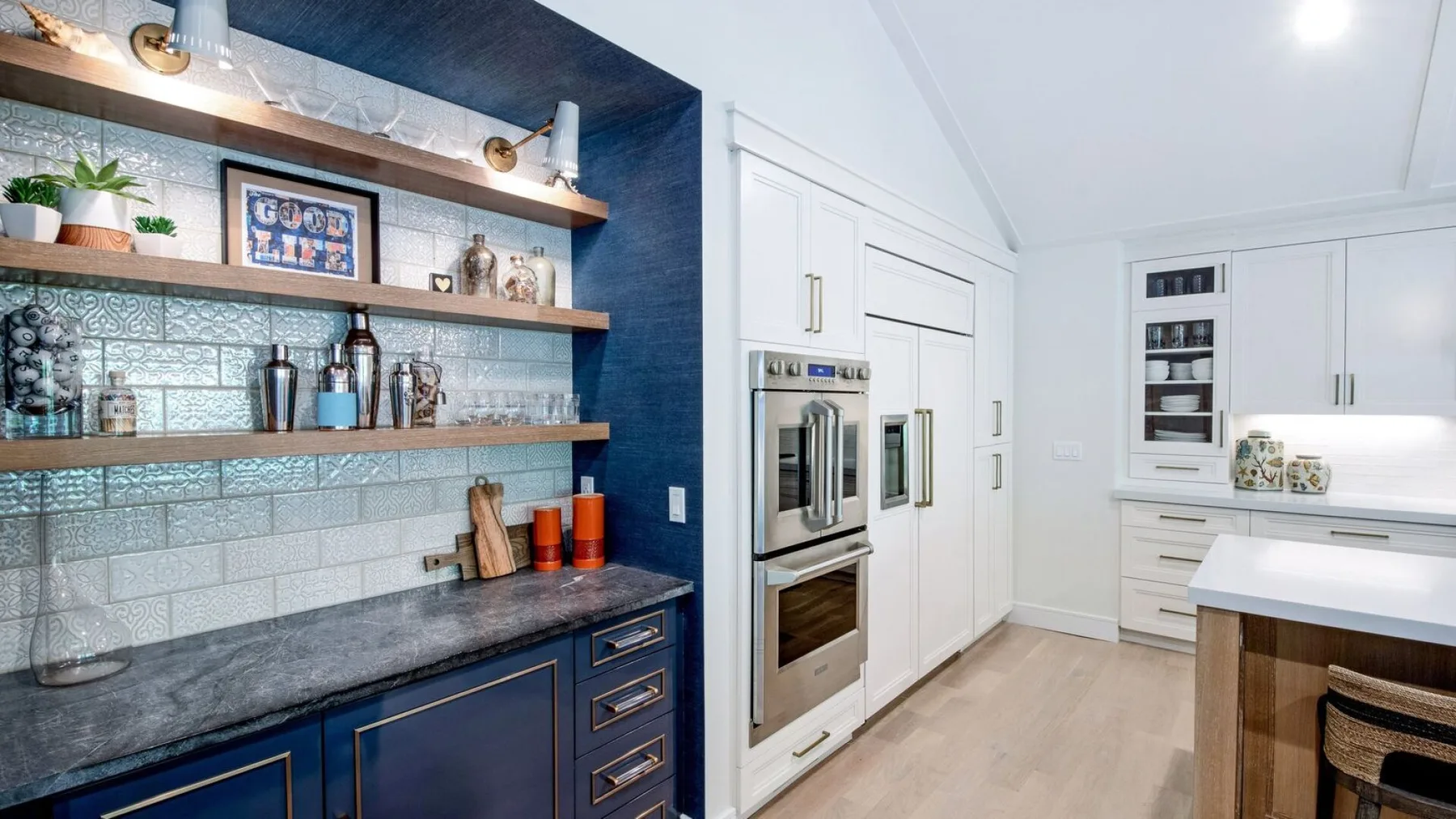 Una cocina luminosa con gabinetes blancos, encimeras azul oscuro y estantes abiertos.