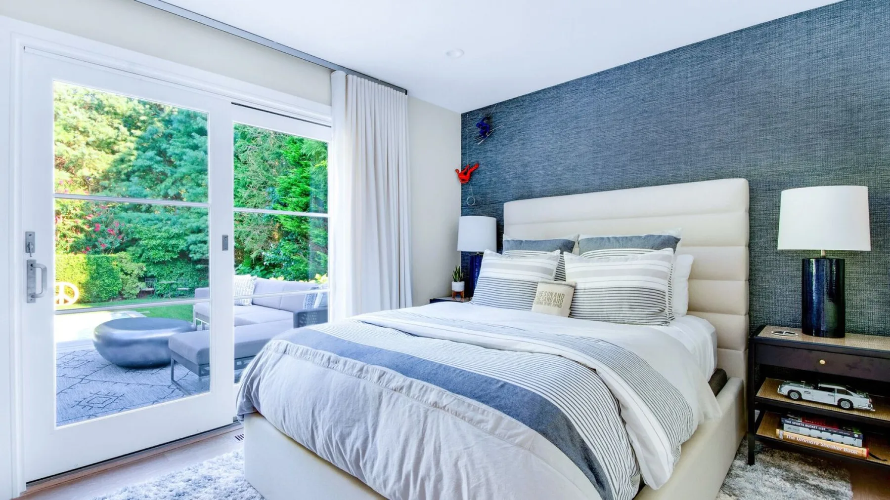 Un dormitorio con una cama tendida junto a puertas de vidrio que dan a un patio.