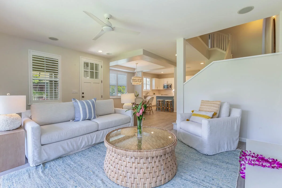 A living room with seating, a round coffee table, and an open kitchen beyond.