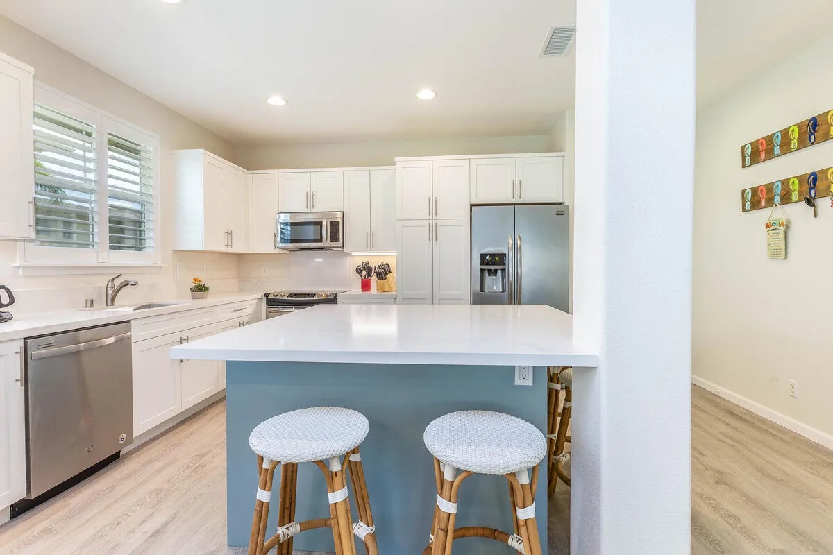 A bright kitchen with white cabinetry and an island with seating.