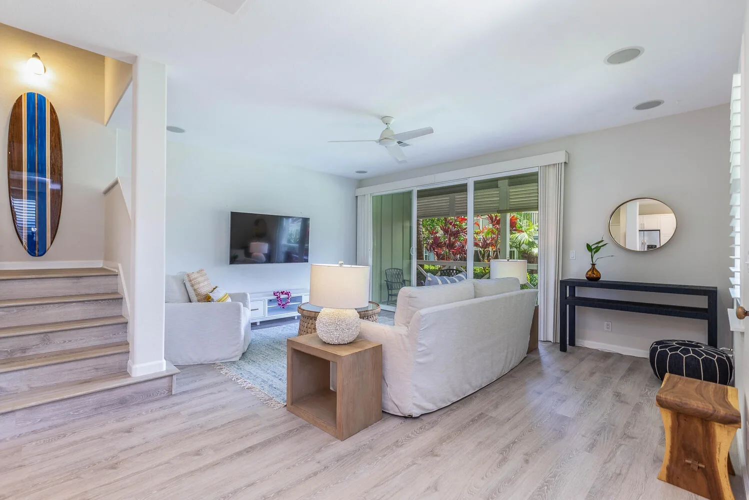 A bright living room with seating arranged around a television and glass doors.