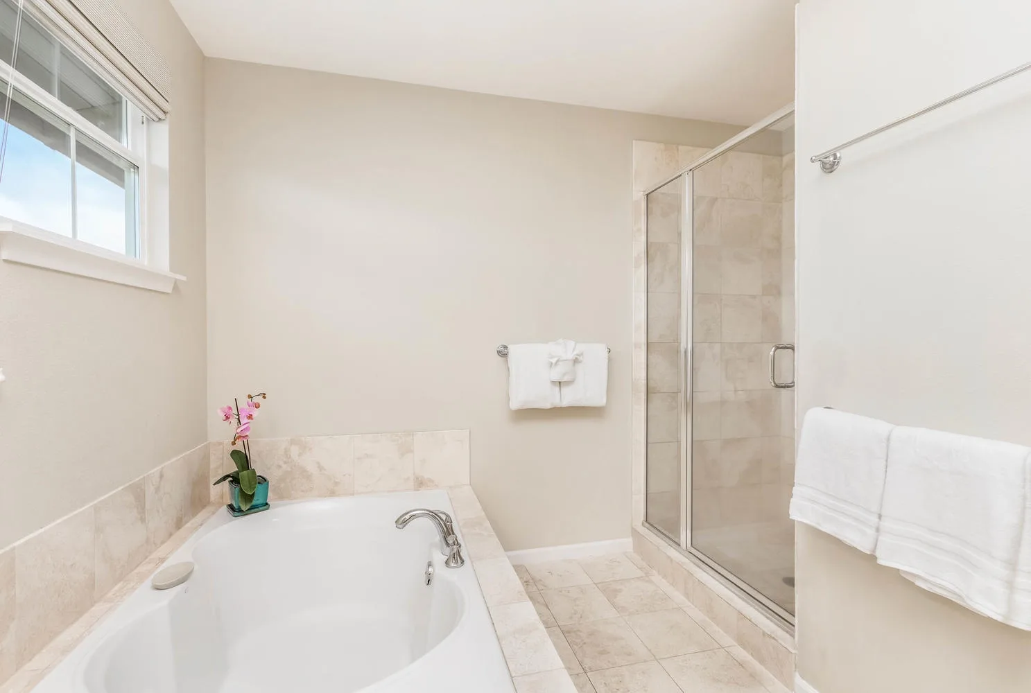 A bright bathroom with a bathtub and glass-enclosed shower.