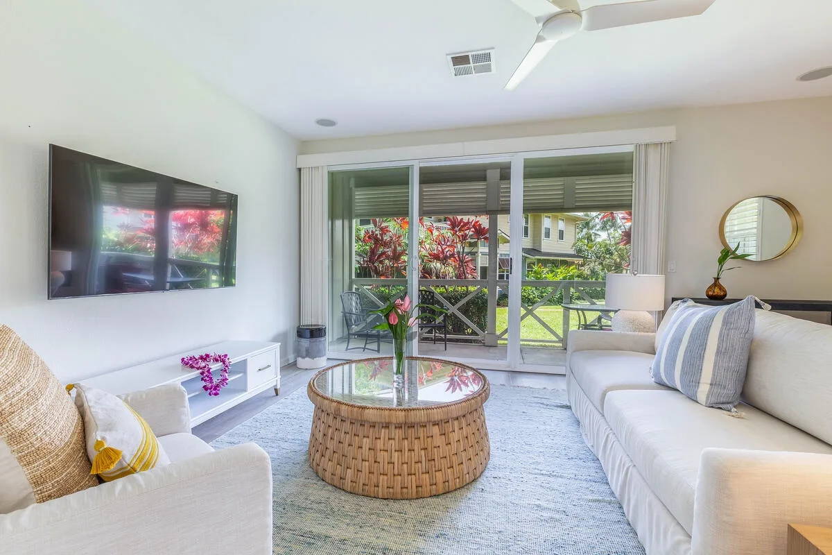 A bright living room with seating, a glass coffee table, and sliding glass doors.