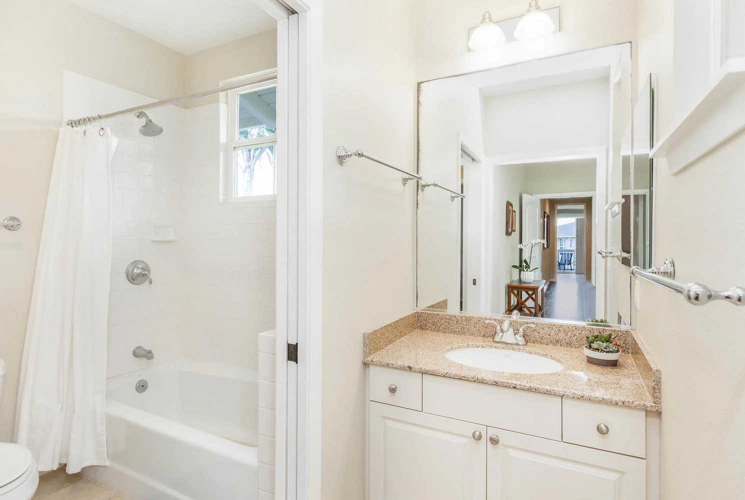 A bright bathroom with a bathtub and a vanity beside a large mirror.