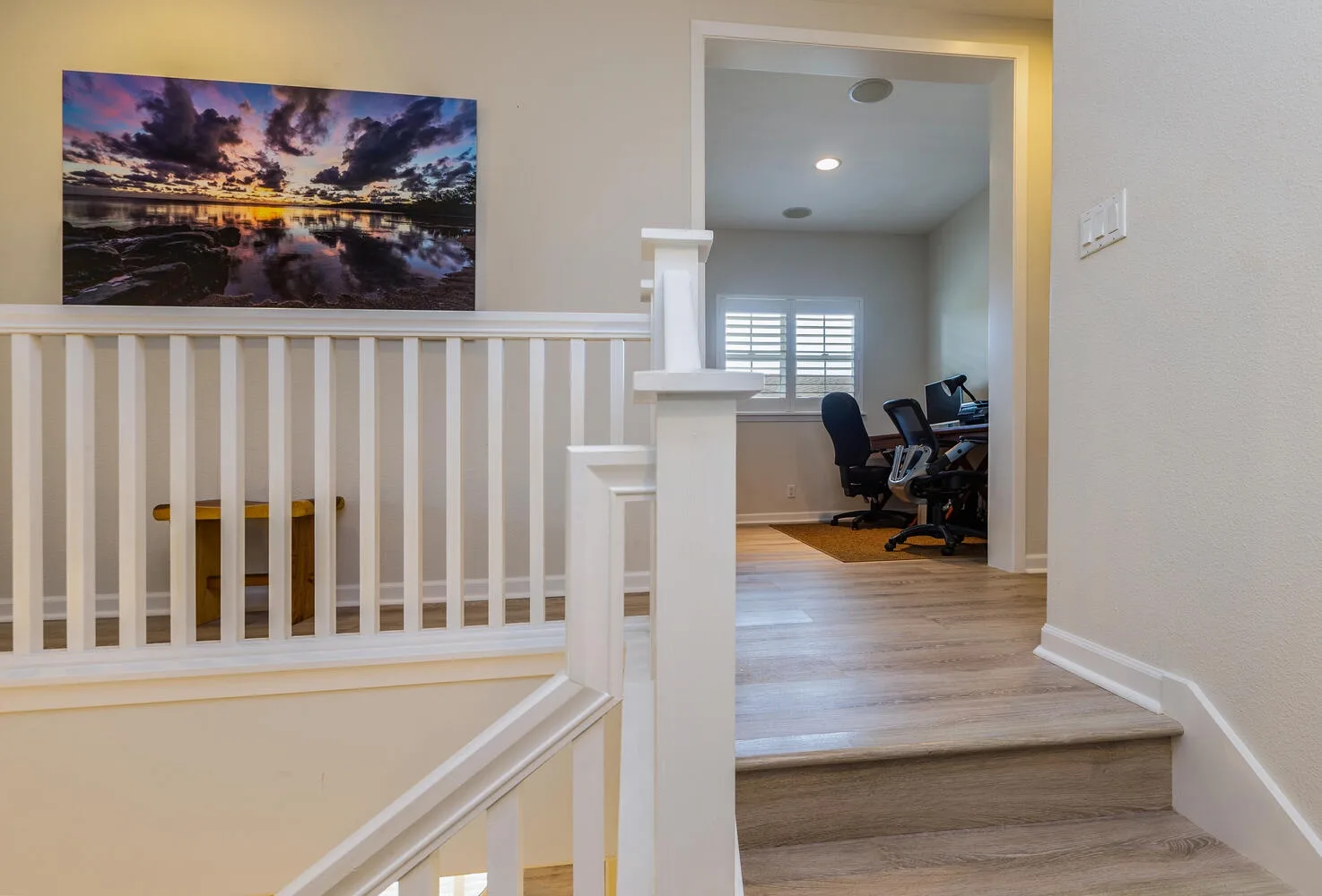 A stair landing opens onto a room with desks and office chairs.