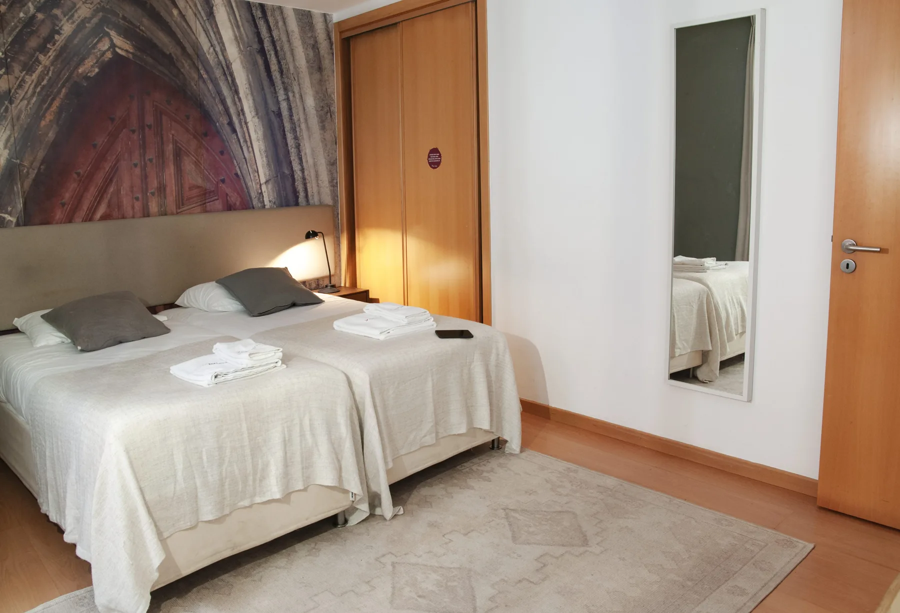 A bedroom with two beds, white linens, and a large mirror.