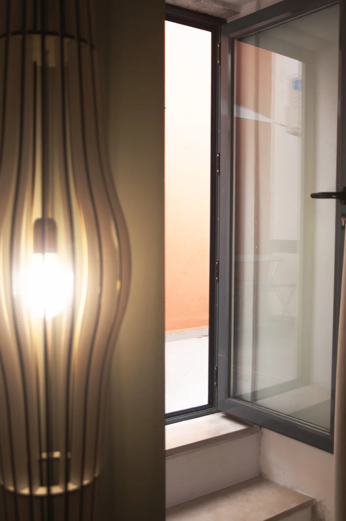 An open window and glowing pendant light brighten a small interior space.
