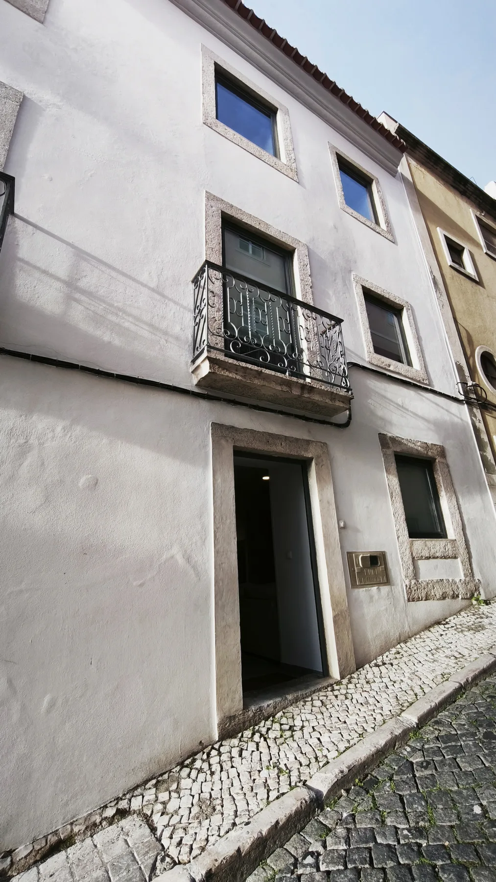 A white building facade with a small iron balcony above the entrance.