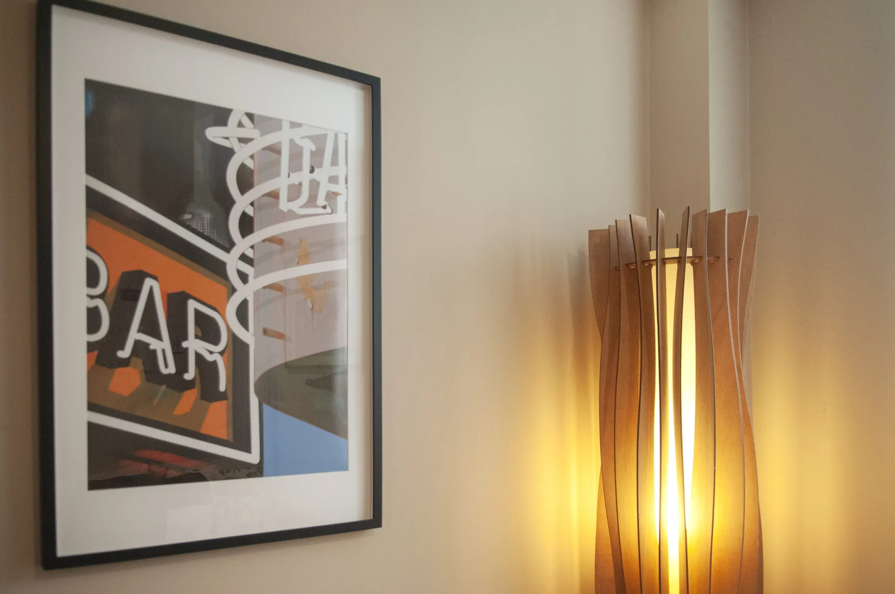 A framed abstract print hangs beside a glowing floor lamp.