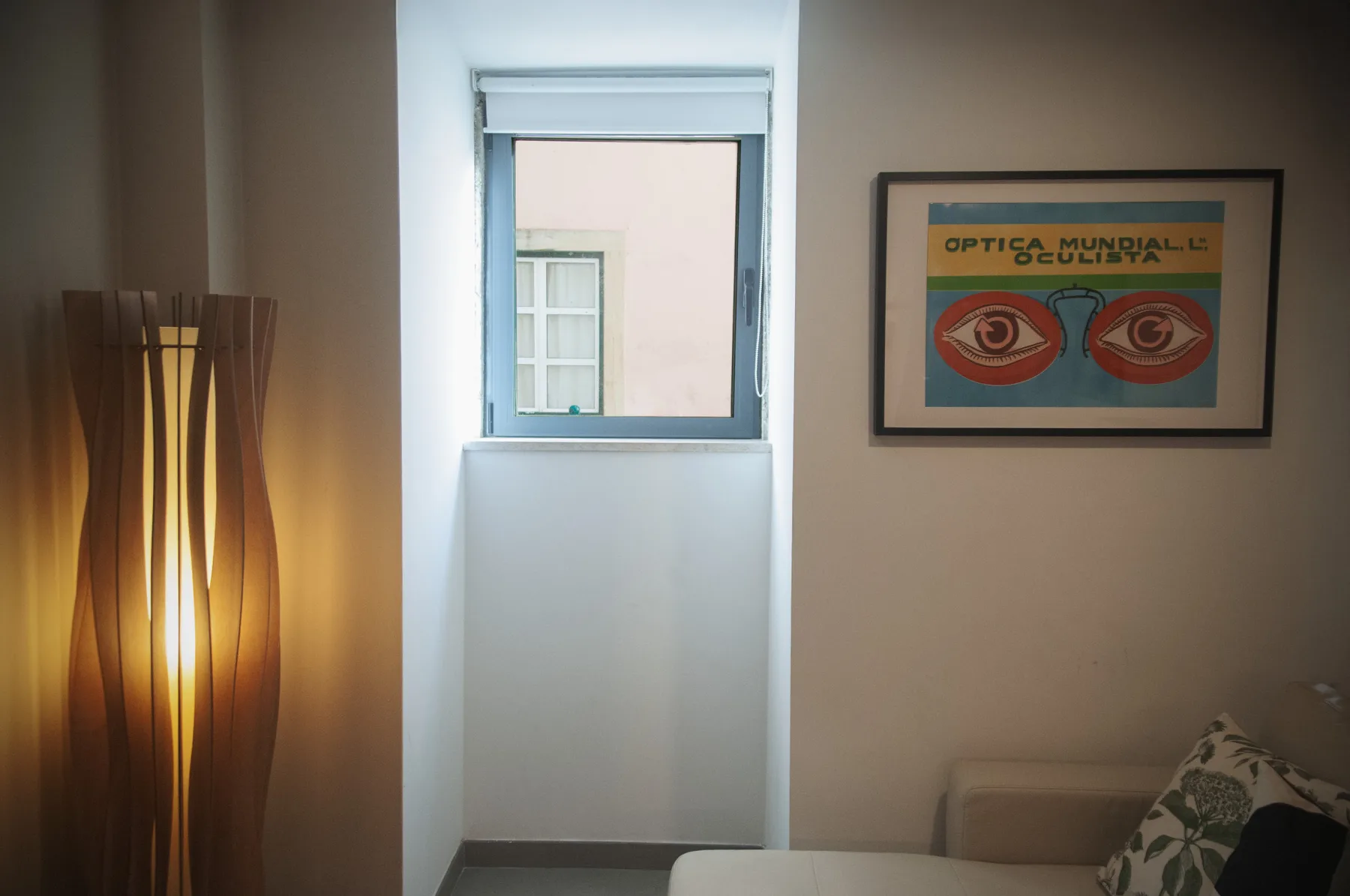A softly lit bedroom with a narrow window and framed artwork.