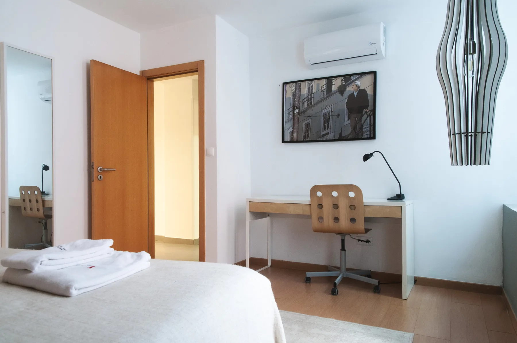 A bedroom with a desk and chair beside the bed.
