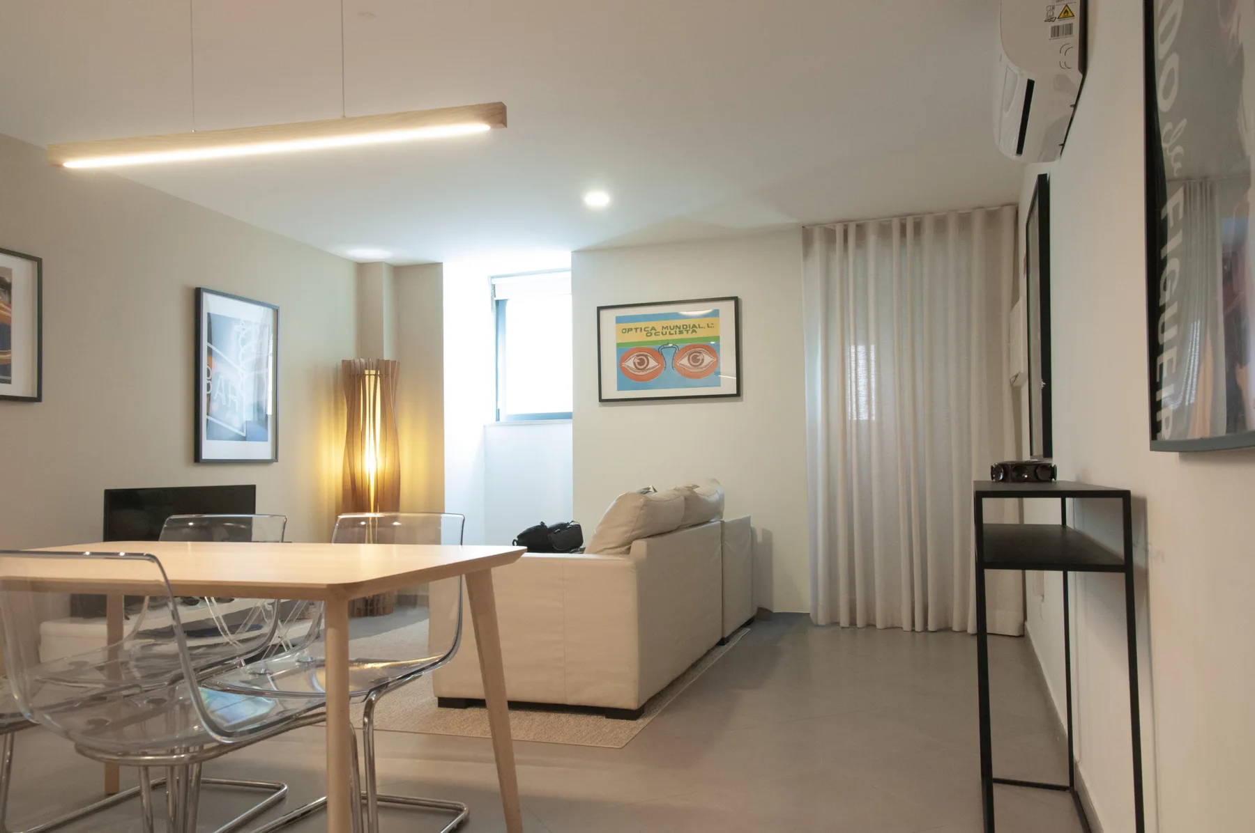 A bright living and dining area with a table, seating, and a curtained window.