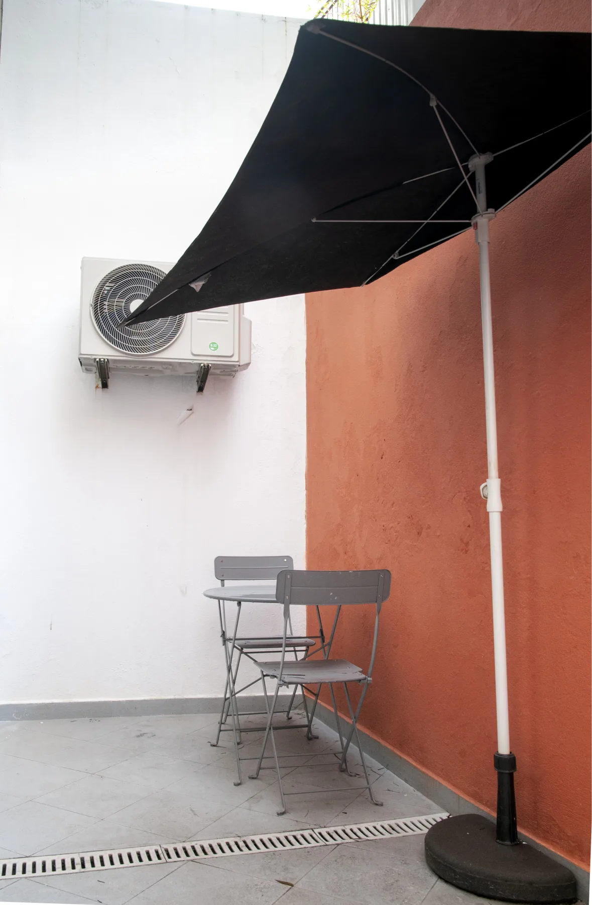 A small terrace has metal seating beneath a black shade canopy.