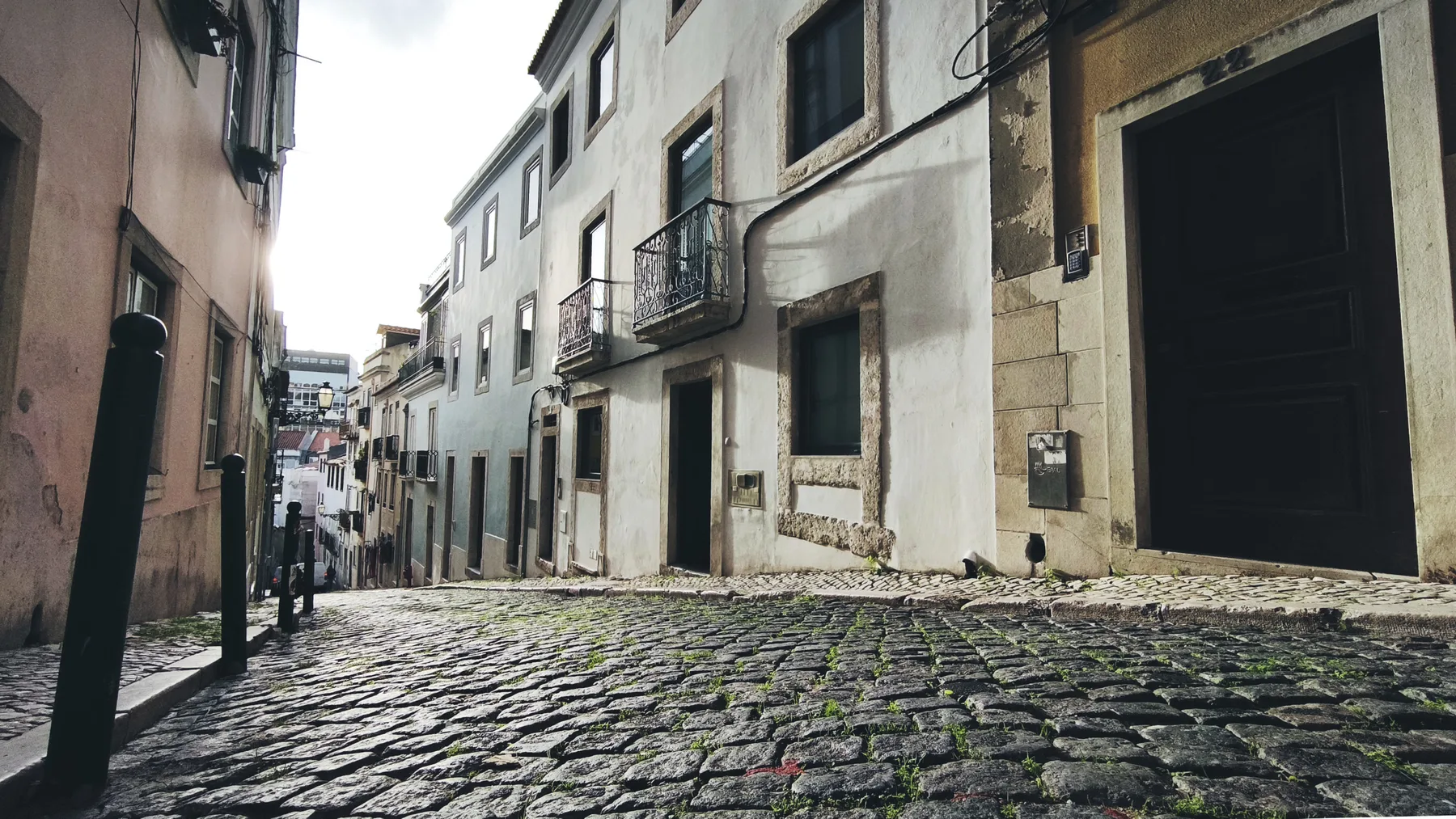 A narrow cobblestone street runs between closely spaced buildings.