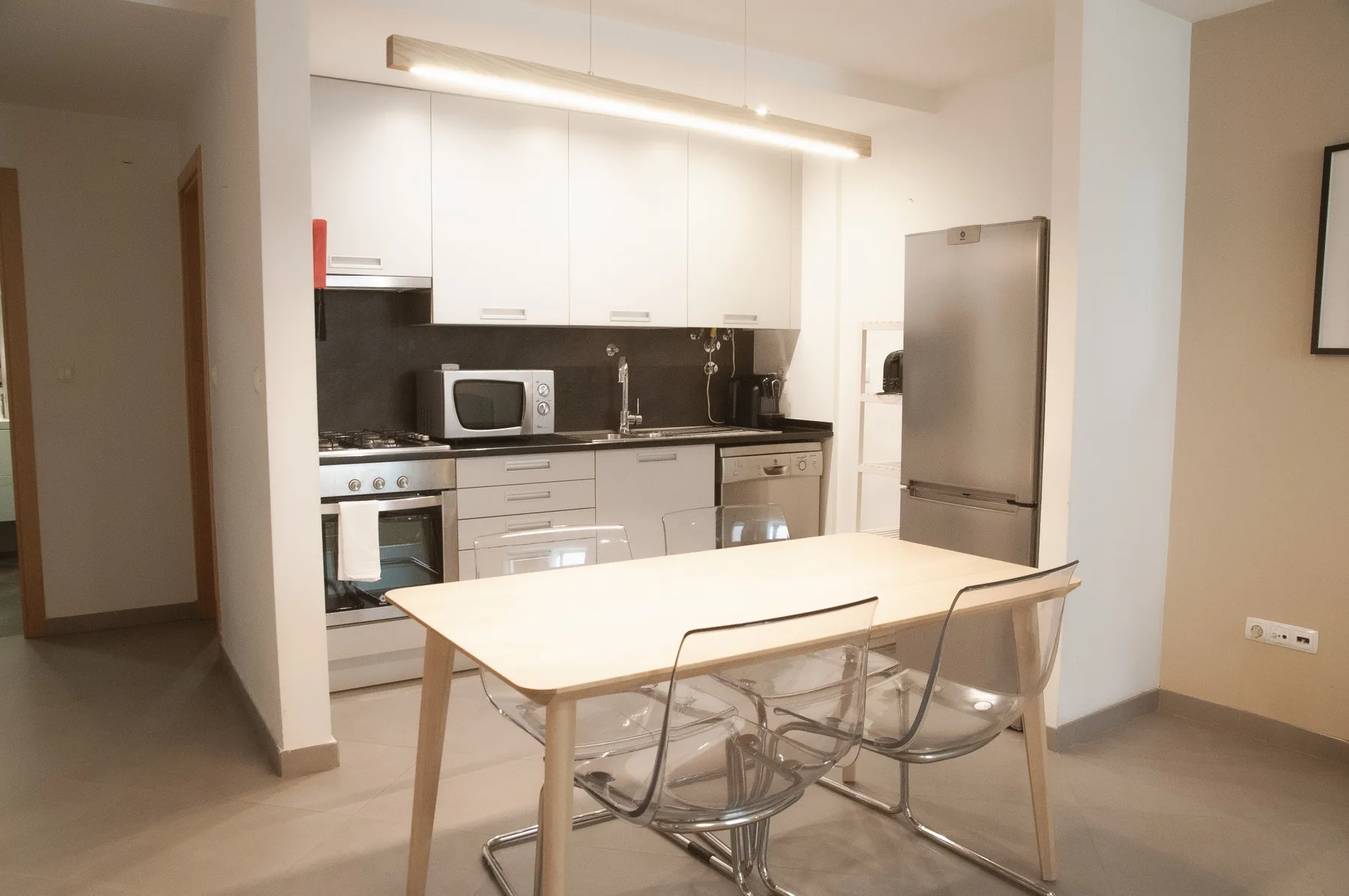 A modern kitchen with white cabinets and a dining table.