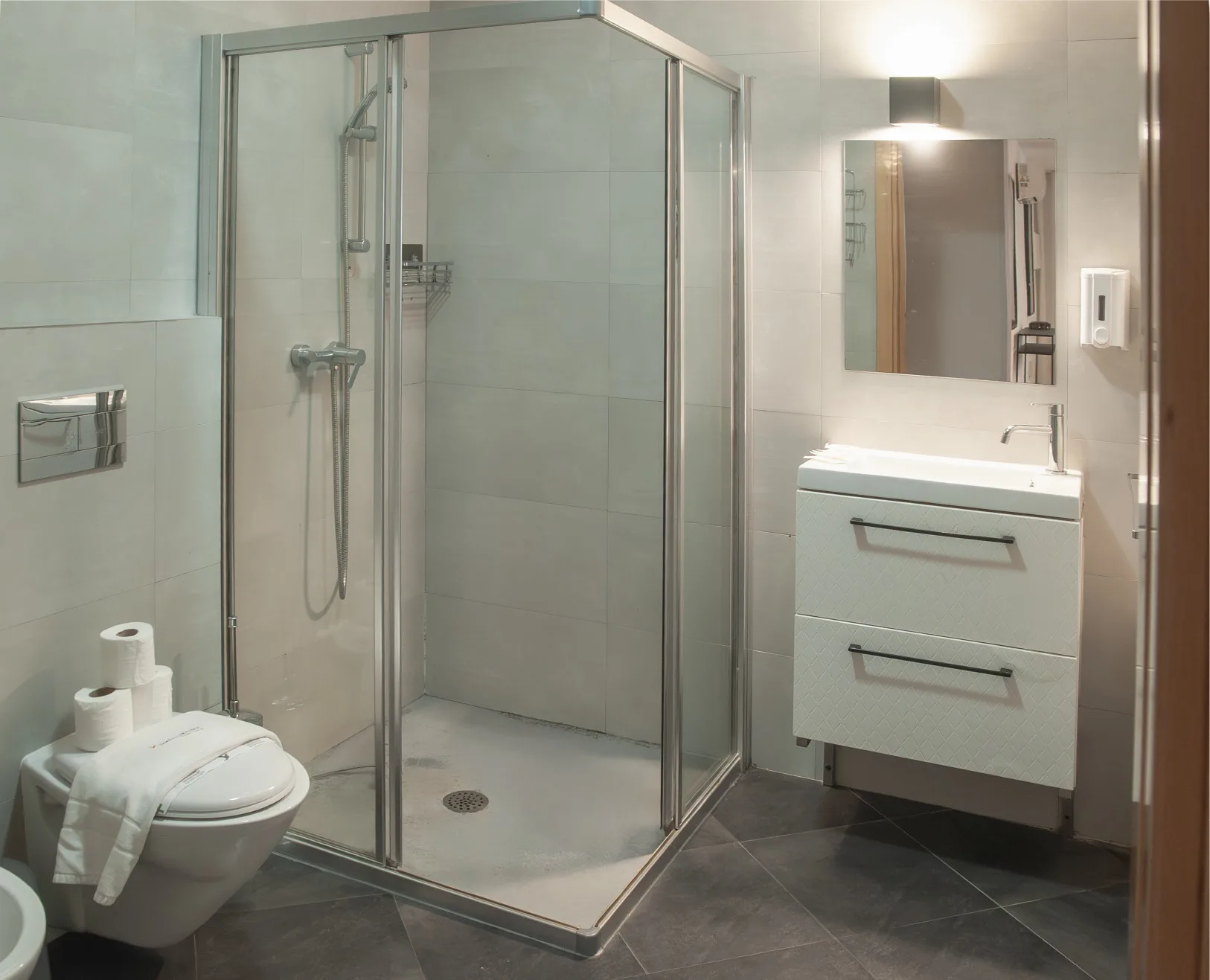 A tiled bathroom with a glass shower and a sink vanity.