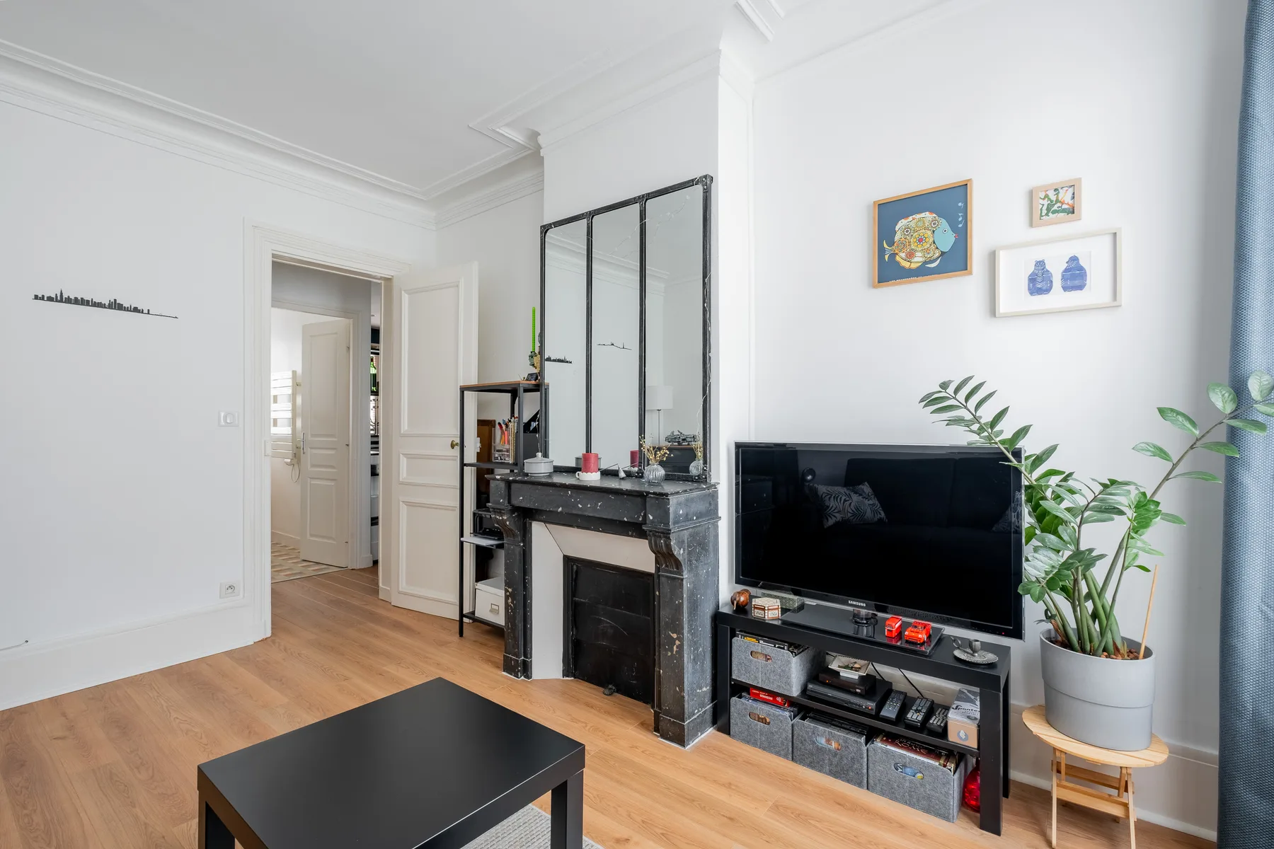 A bright living room with a television, fireplace, and framed artwork.