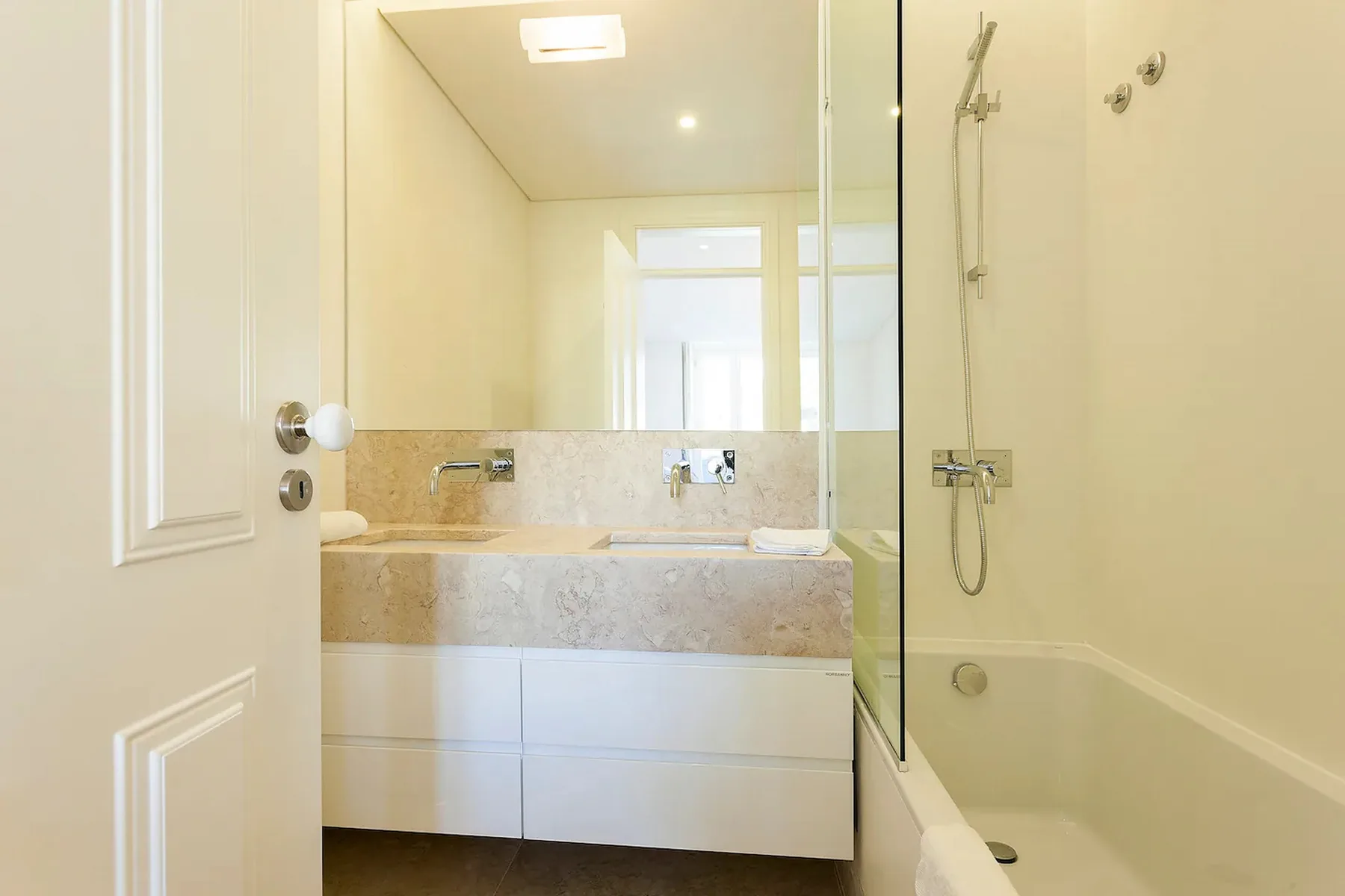 Un baño luminoso con un lavabo amplio y una bañera con ducha.