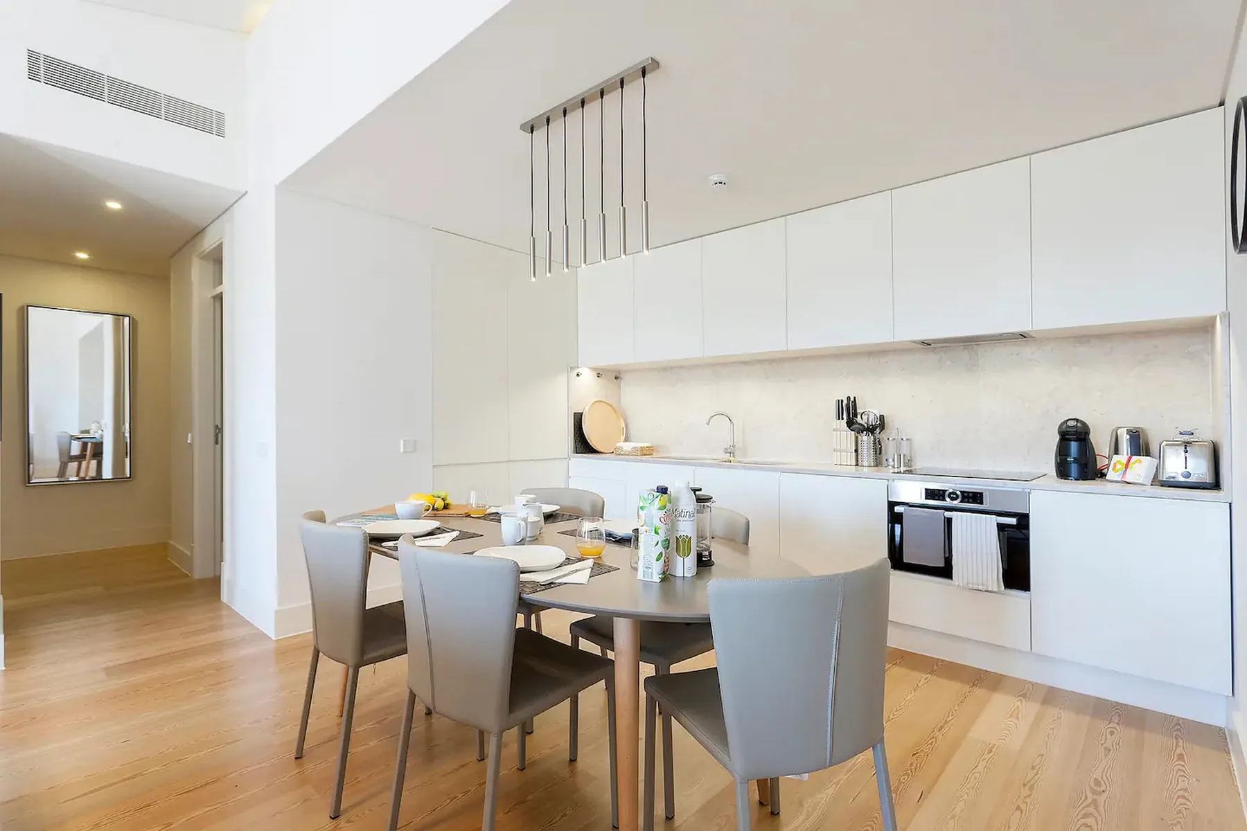 Un comedor con mesa y sillas junto a una cocina luminosa.