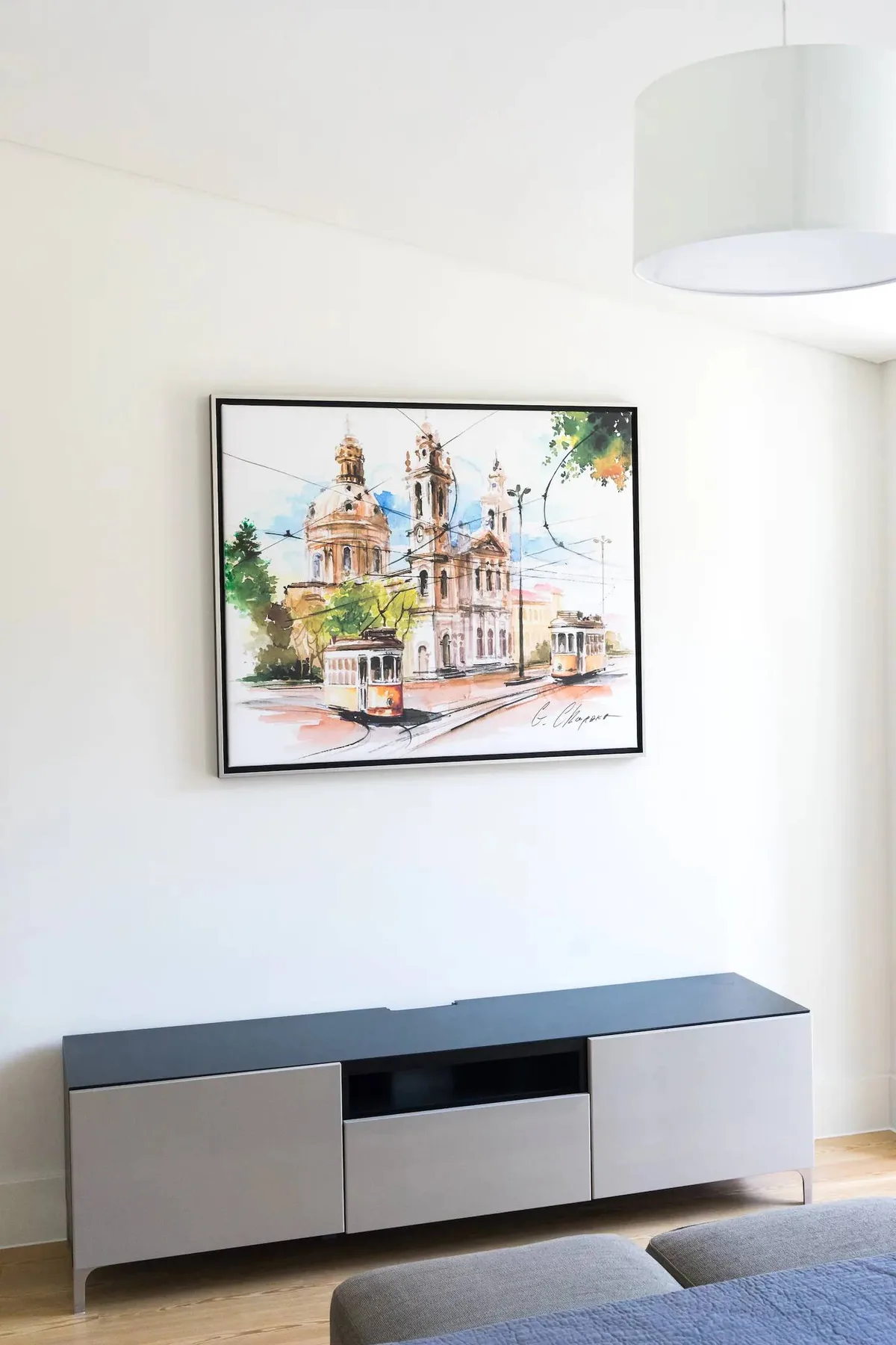 Una sala luminosa presenta una obra enmarcada sobre un mueble bajo.