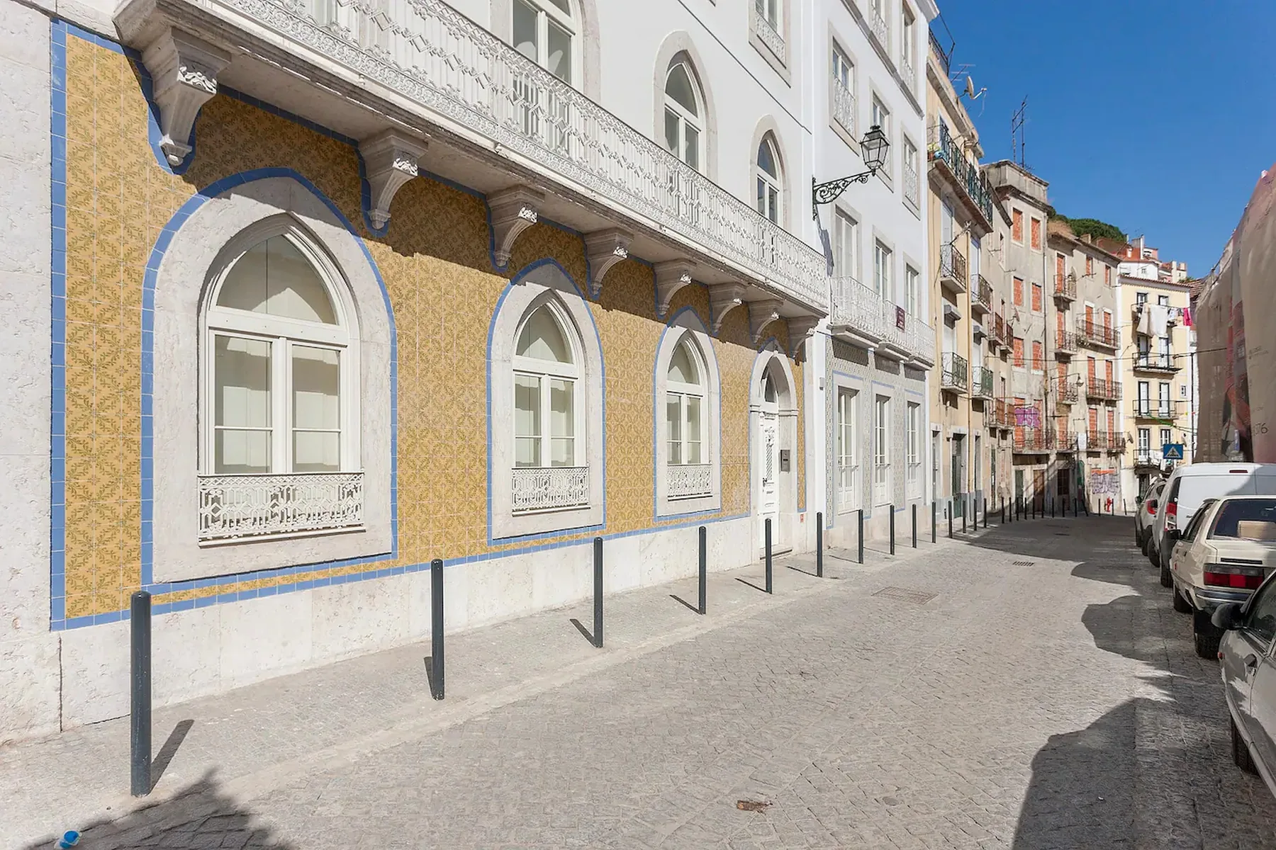 Una calle soleada con fachadas coloridas y coches estacionados.