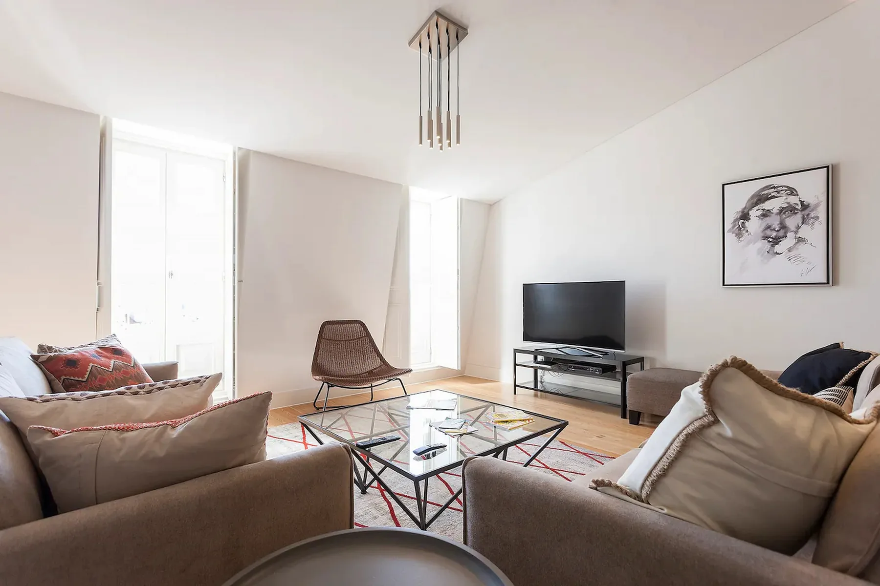 Una sala de estar luminosa con asientos alrededor de una mesa de centro de vidrio y un televisor.