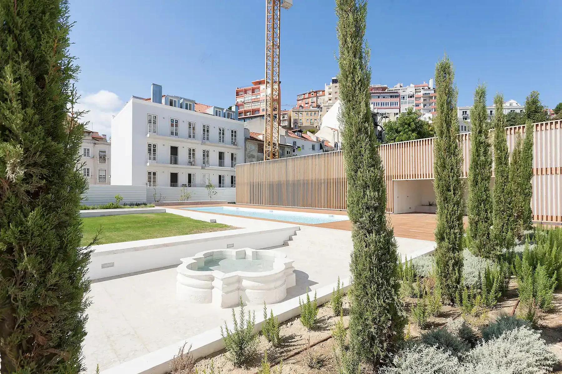 Un patio ajardinado con una piscina pequeña y edificios modernos.