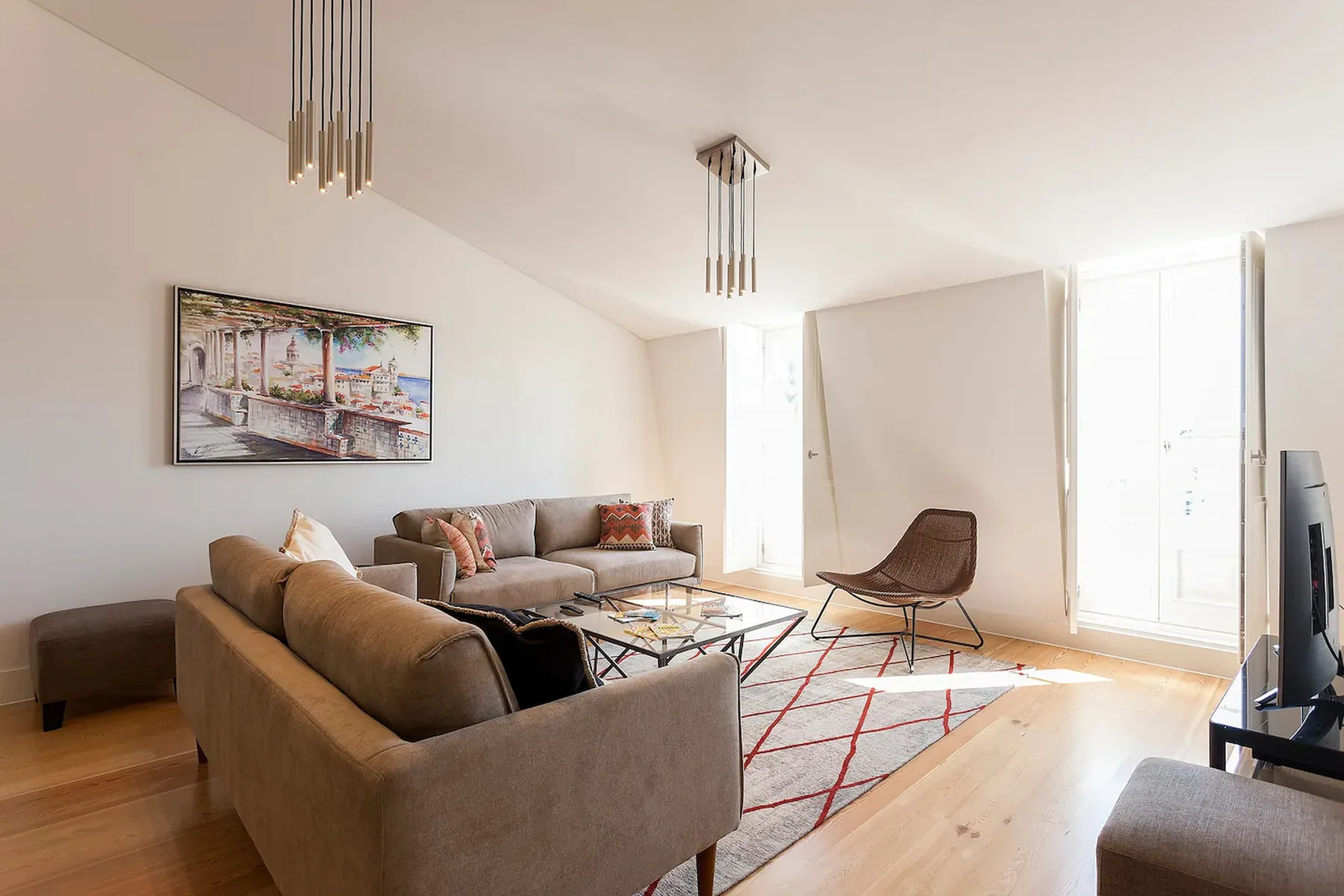 Una sala de estar luminosa con asientos alrededor de una mesa baja y una alfombra estampada.
