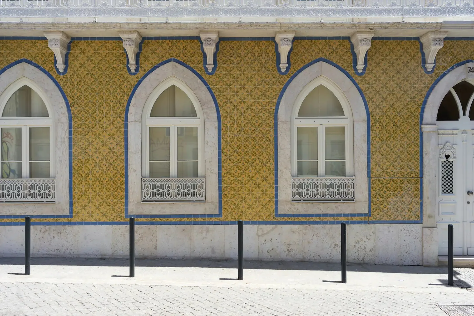 Una fachada colorida con ventanas arqueadas y una entrada decorativa.