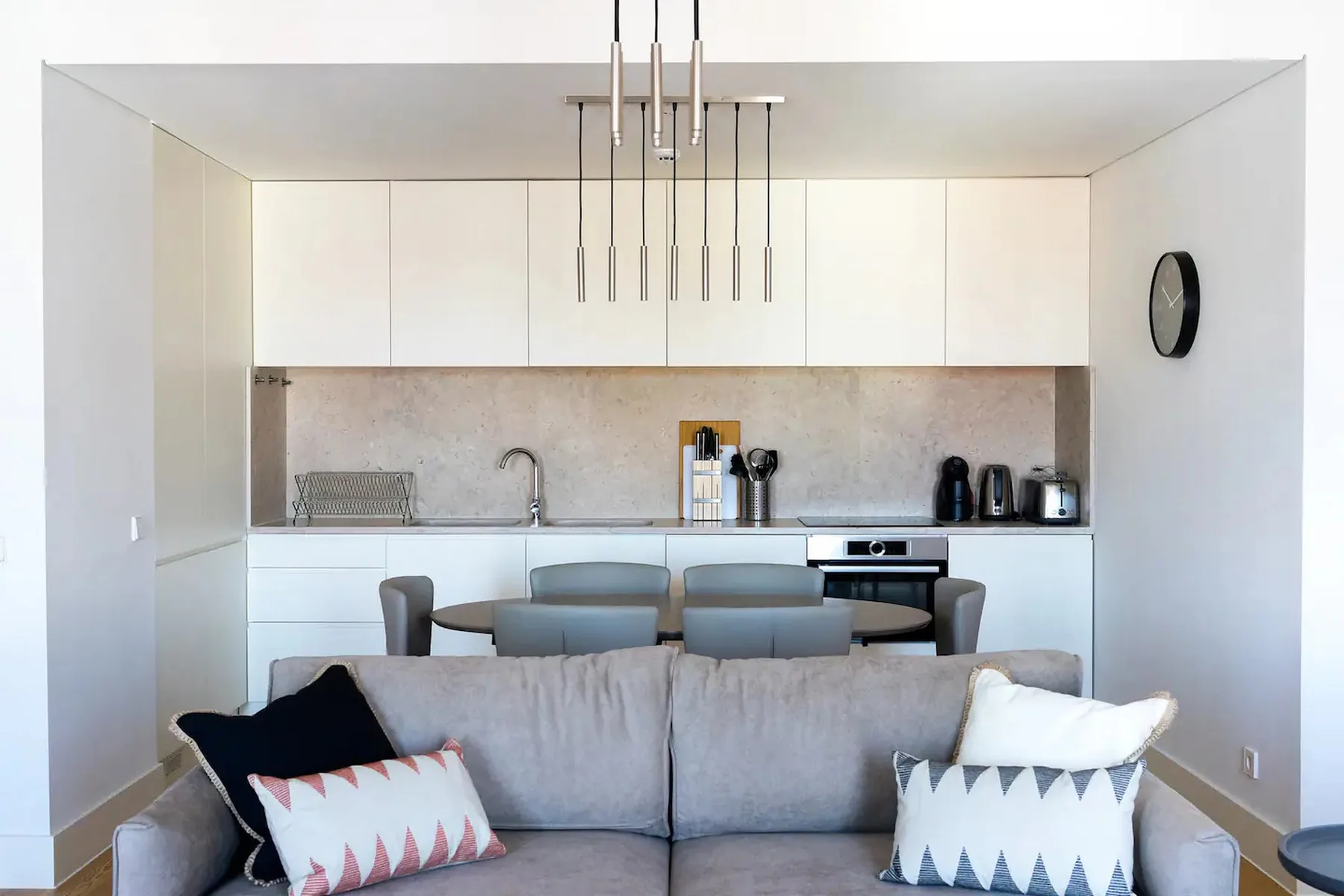 Una sala de estar luminosa con sofá, mesa de comedor y cocina abierta.