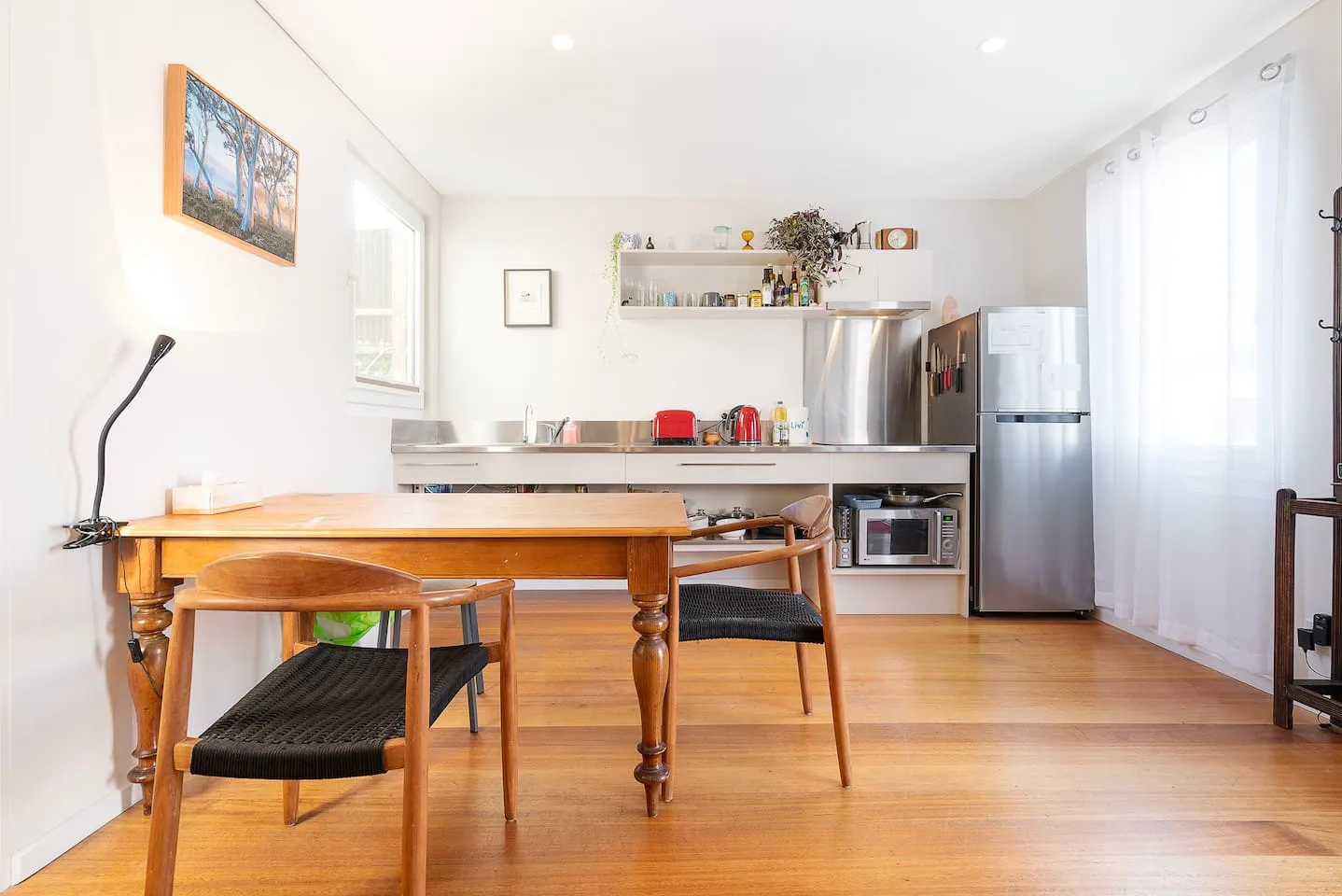 Un comedor con una mesa de madera y sillas está junto a una cocina abierta.