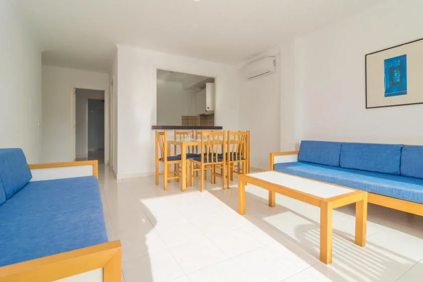 A bright living room with blue seating and a dining table behind it.